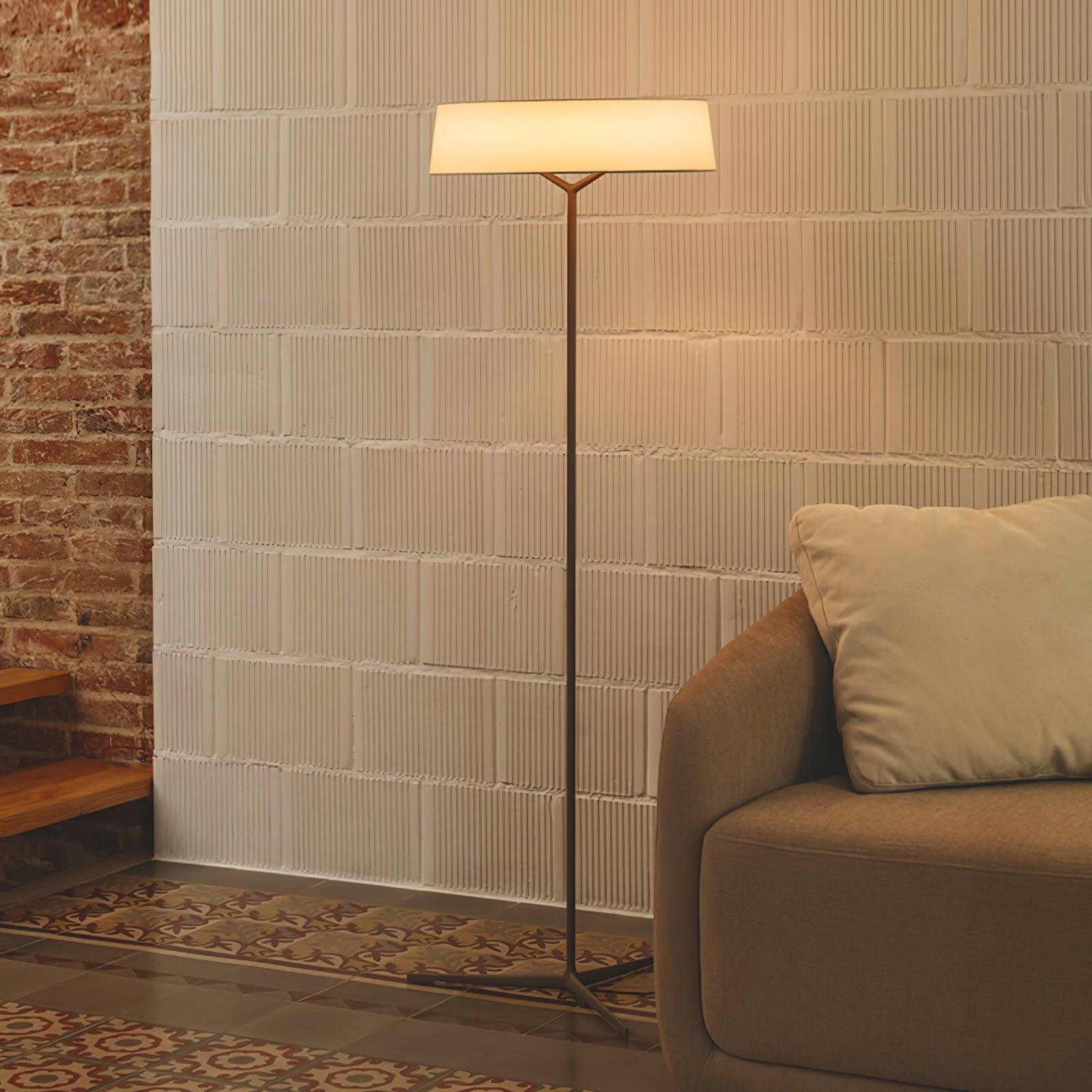 Circular-shade floor lamp near a stone-block wall