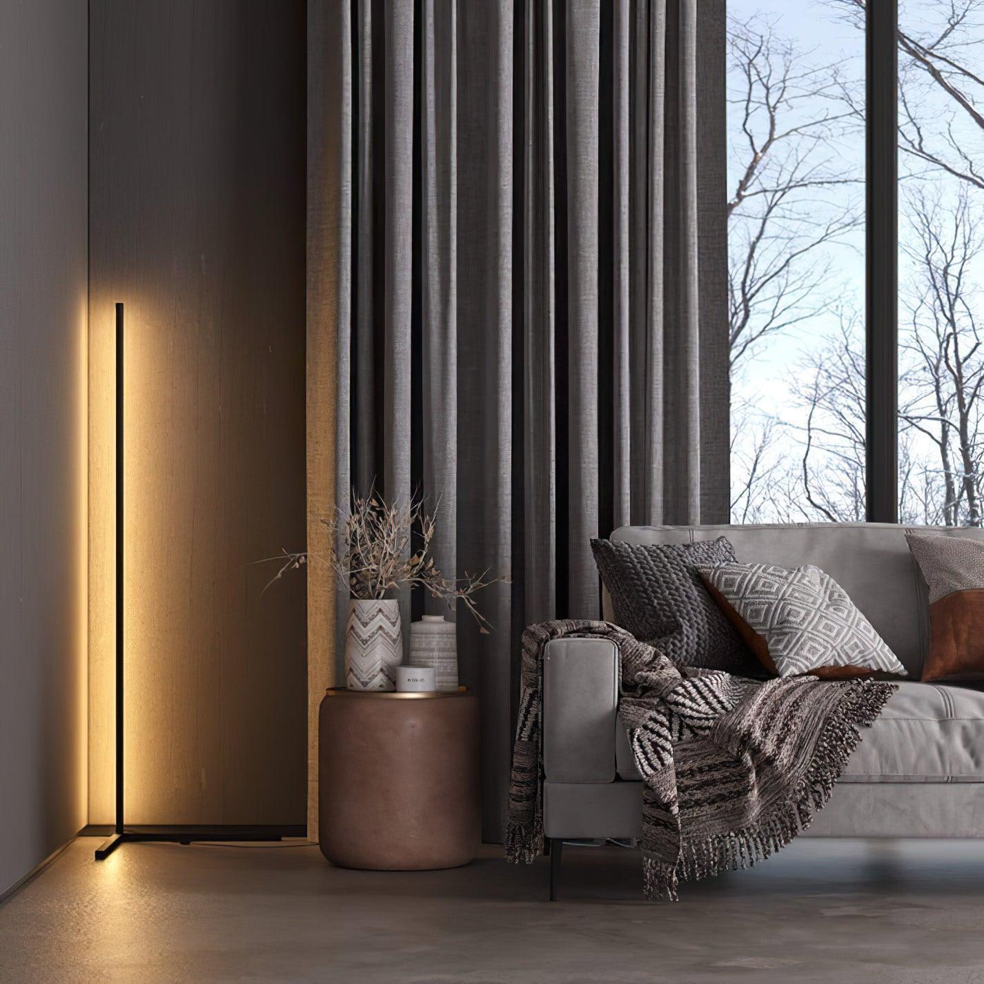 Wide living-room view of a black corner lamp beside a grey sofa, side table and tall curtains