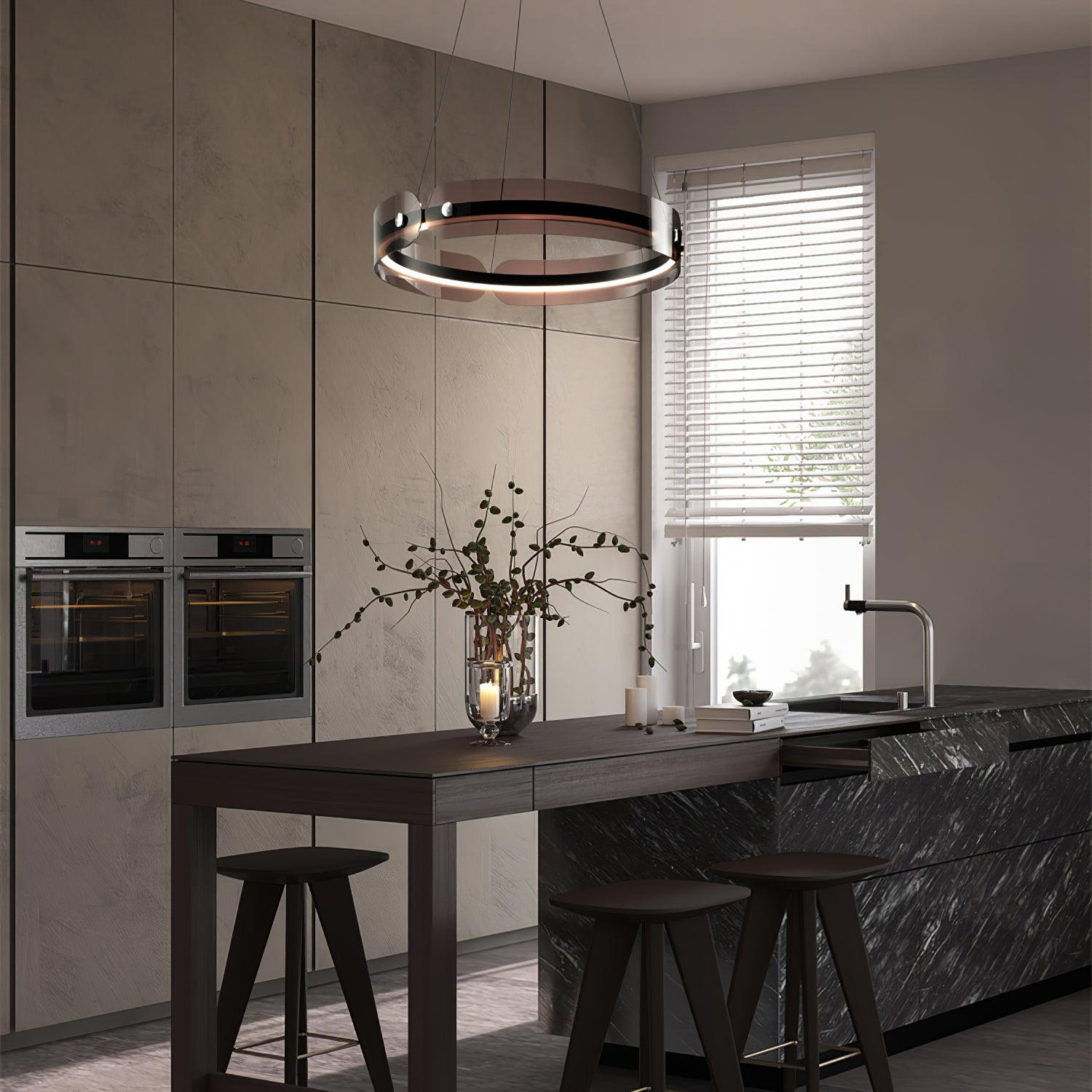 Javor ring chandelier above a dark wood table joined to a black kitchen island with stools and a branch-filled vase