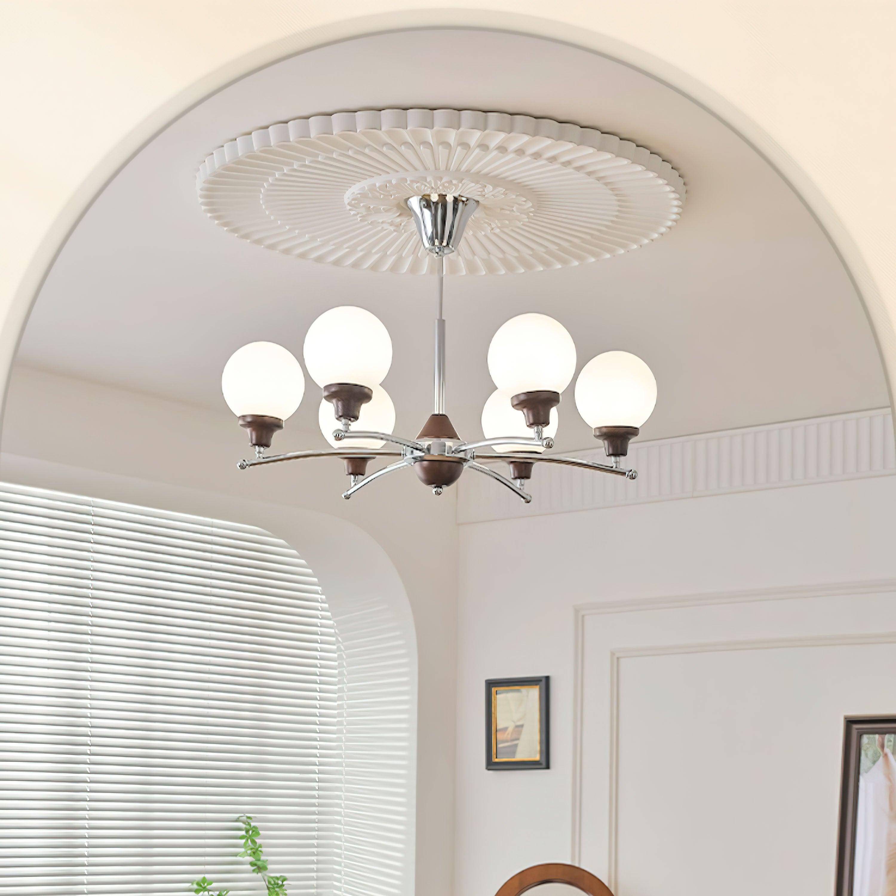 Six-light chrome and walnut chandelier illuminated beneath a room arch, with window blinds and framed artwork