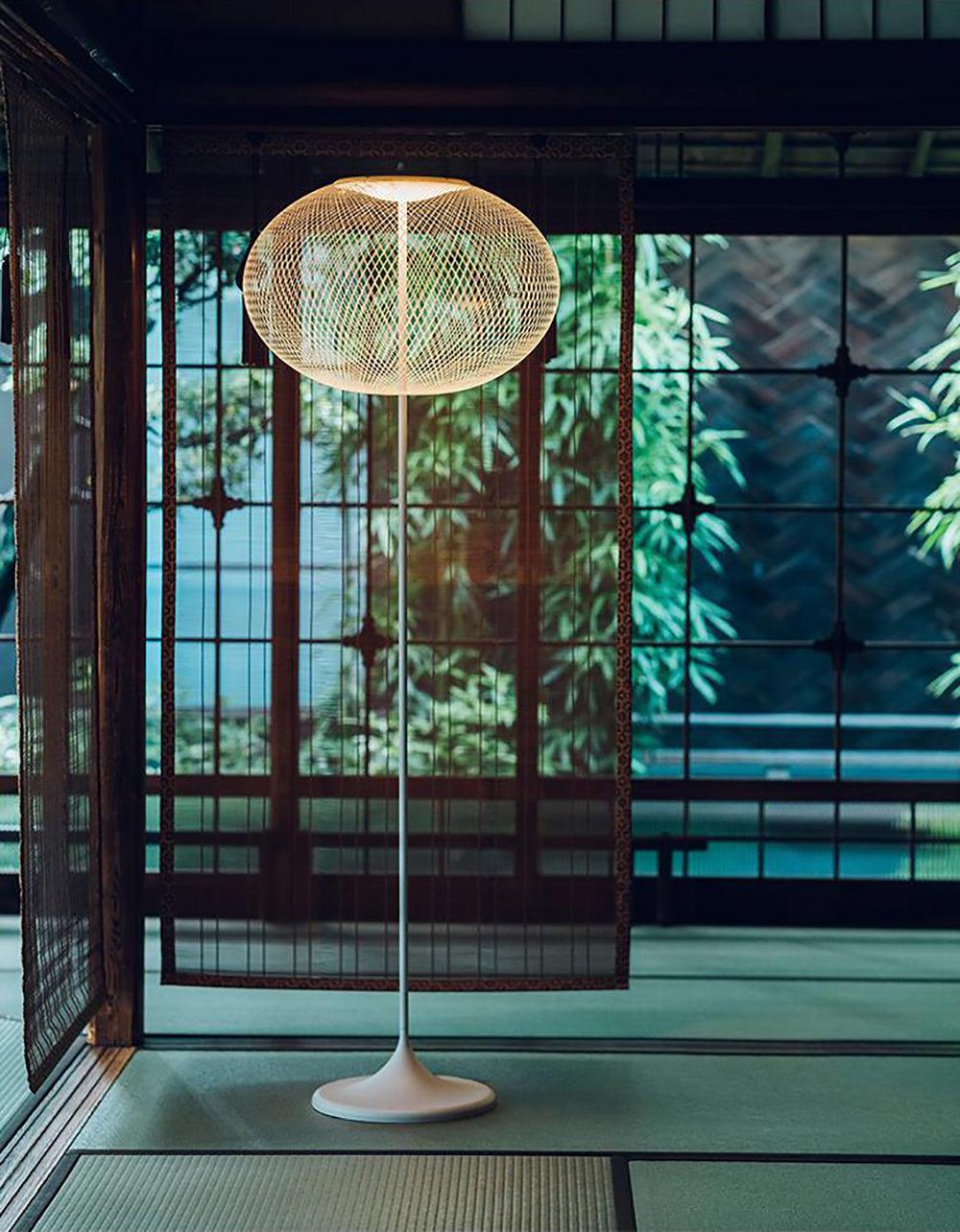 White mesh floor lamp in front of wood-framed screens and garden-facing windows in a tatami-style room