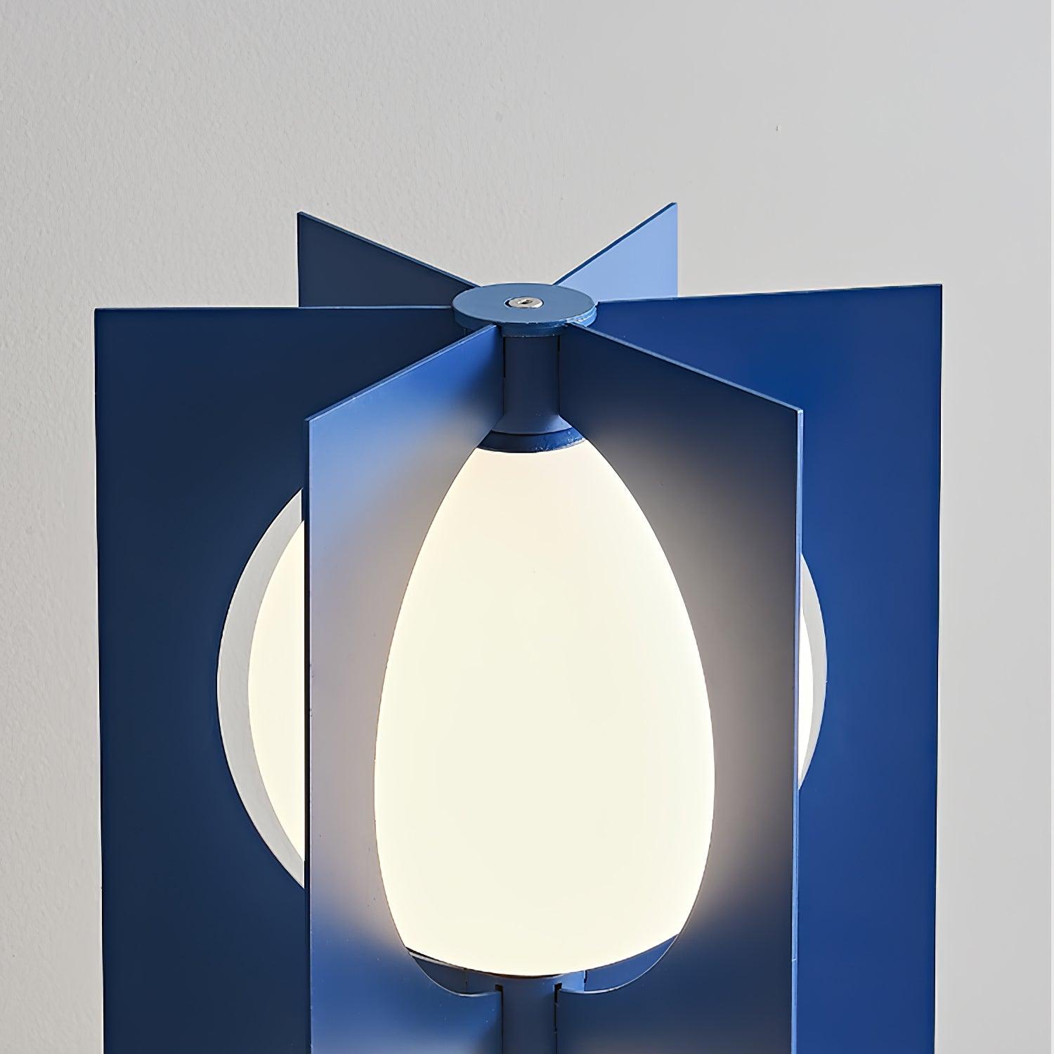 Top close-up of radial blue metal fins, circular cap and glowing white shade