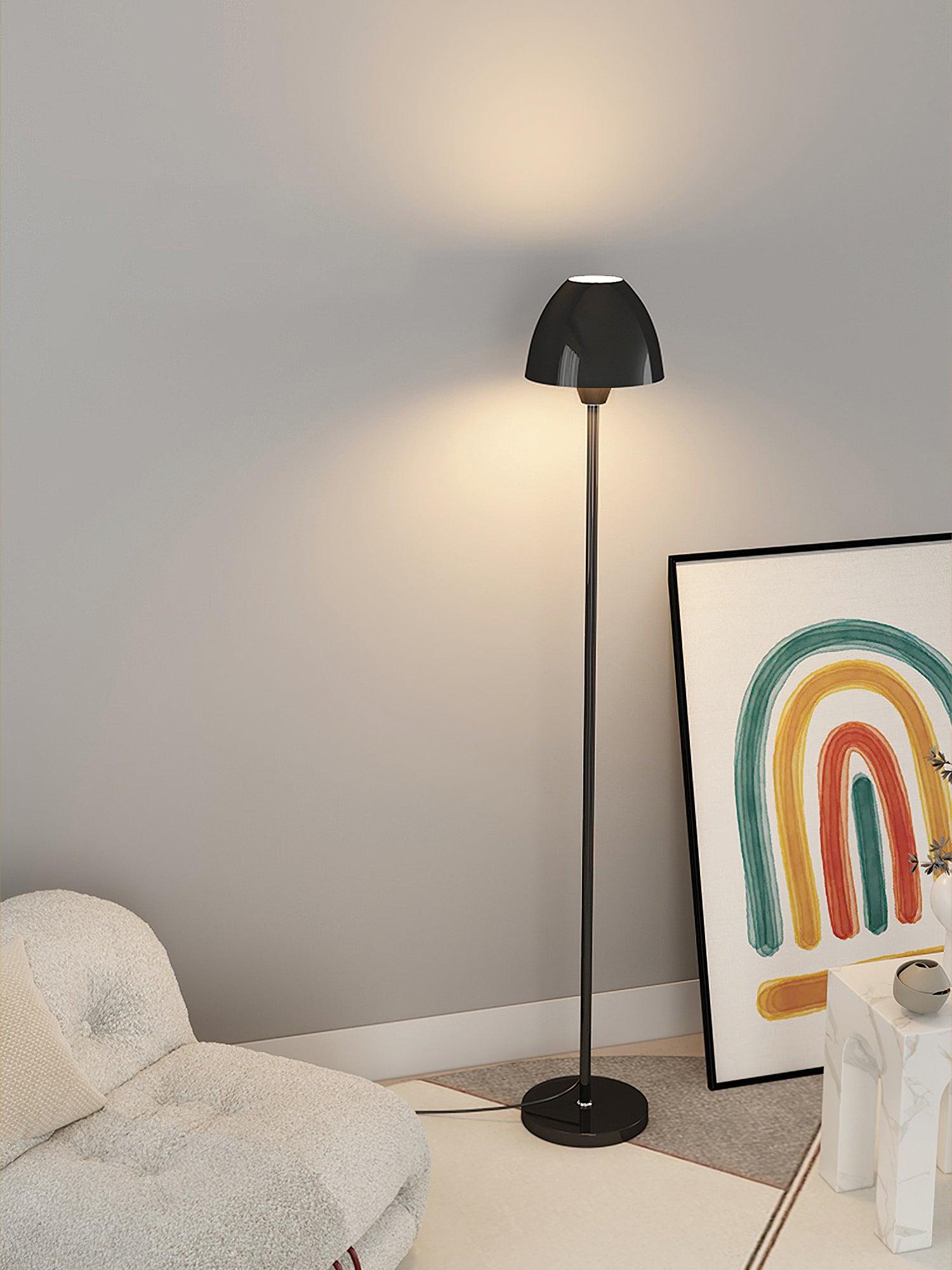 Tall view of a black floor lamp beside a pale chair, rainbow artwork and patterned side table