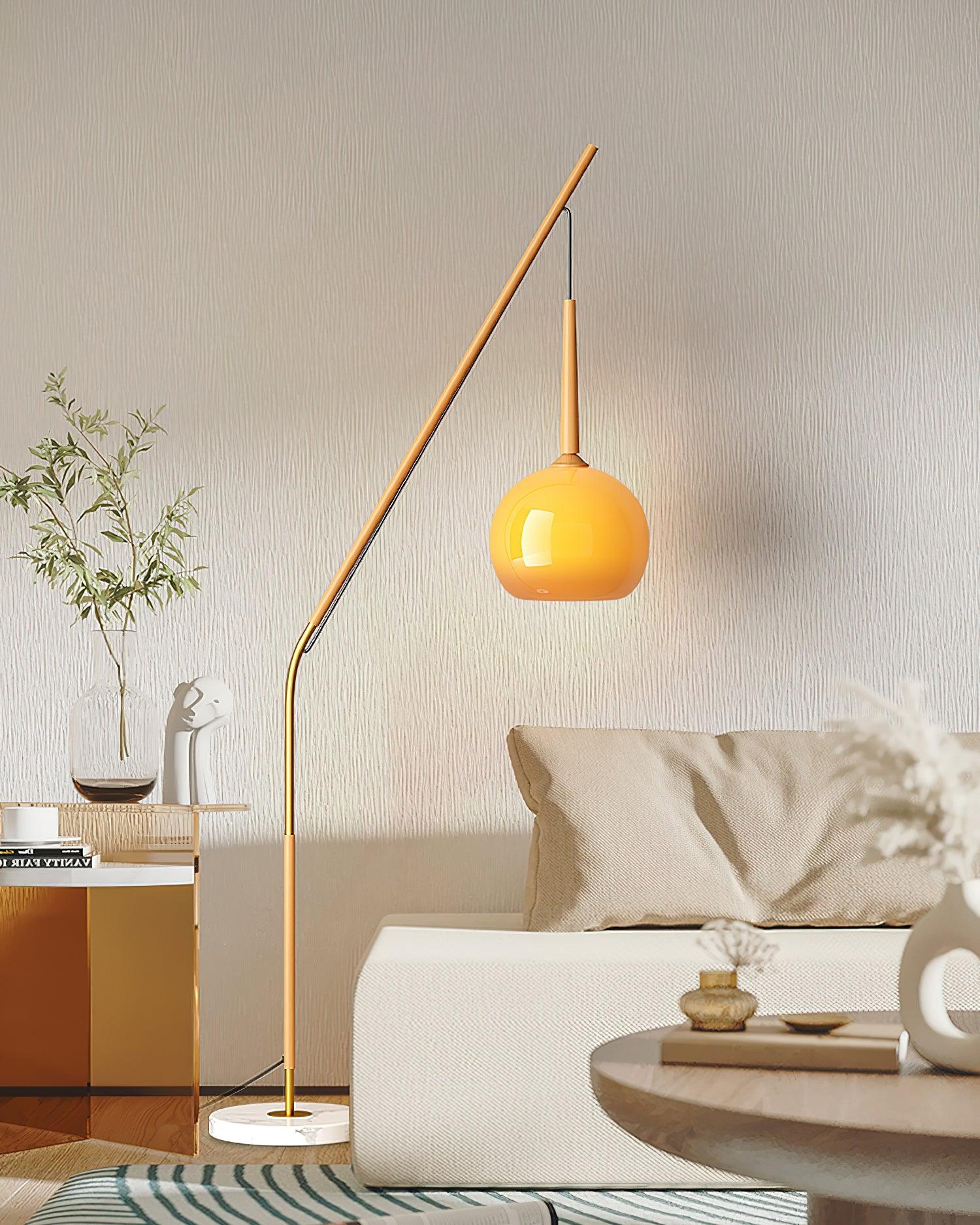 Natural wood-colour Hulusi with orange hanging shade and marble base beside a cream sofa and glass-topped side table