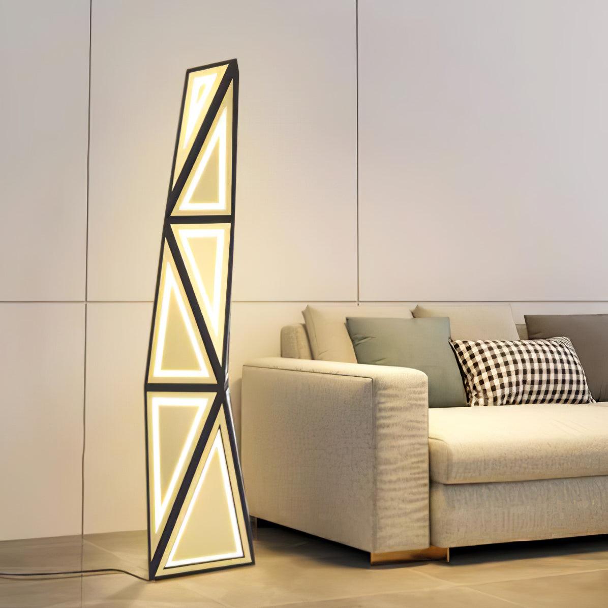 Lit black and gold floor lamp beside a beige sofa with green-grey and checked cushions on tiled flooring