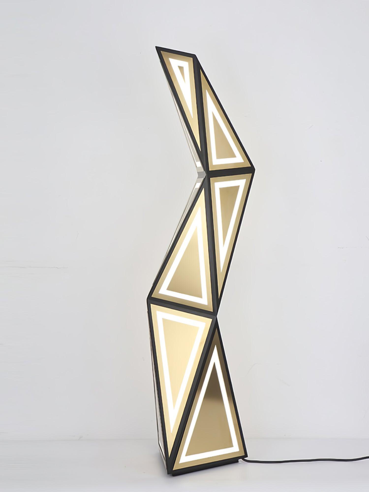 Closer full view of the black and gold tower with triangular light outlines on a pale background