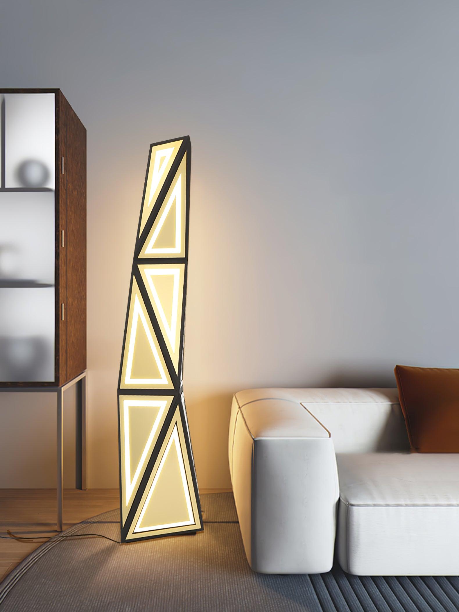 Black and gold angular floor lamp beside a white armchair and wood-and-glass display cabinet