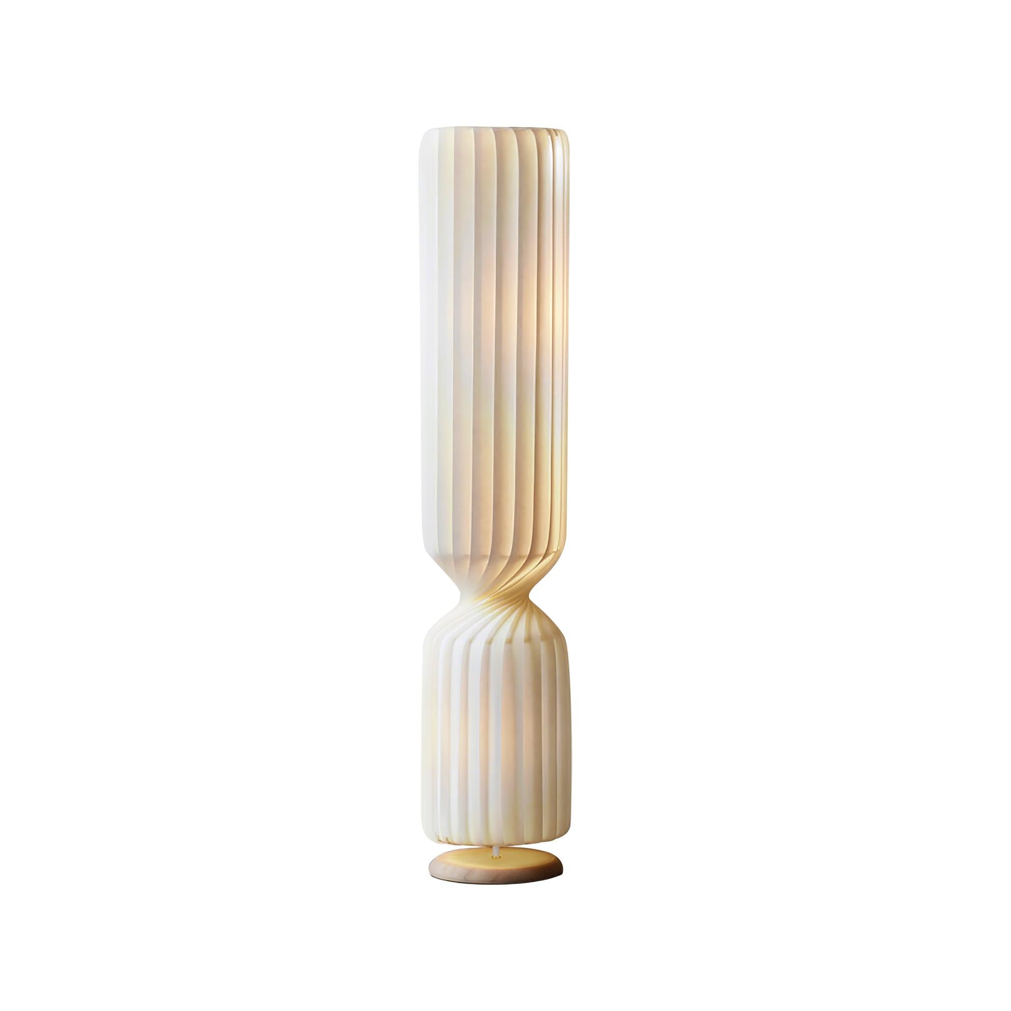 Large isolated lit white Twist floor lamp on white, with pleats, narrow twisted waist, short lower section and round base