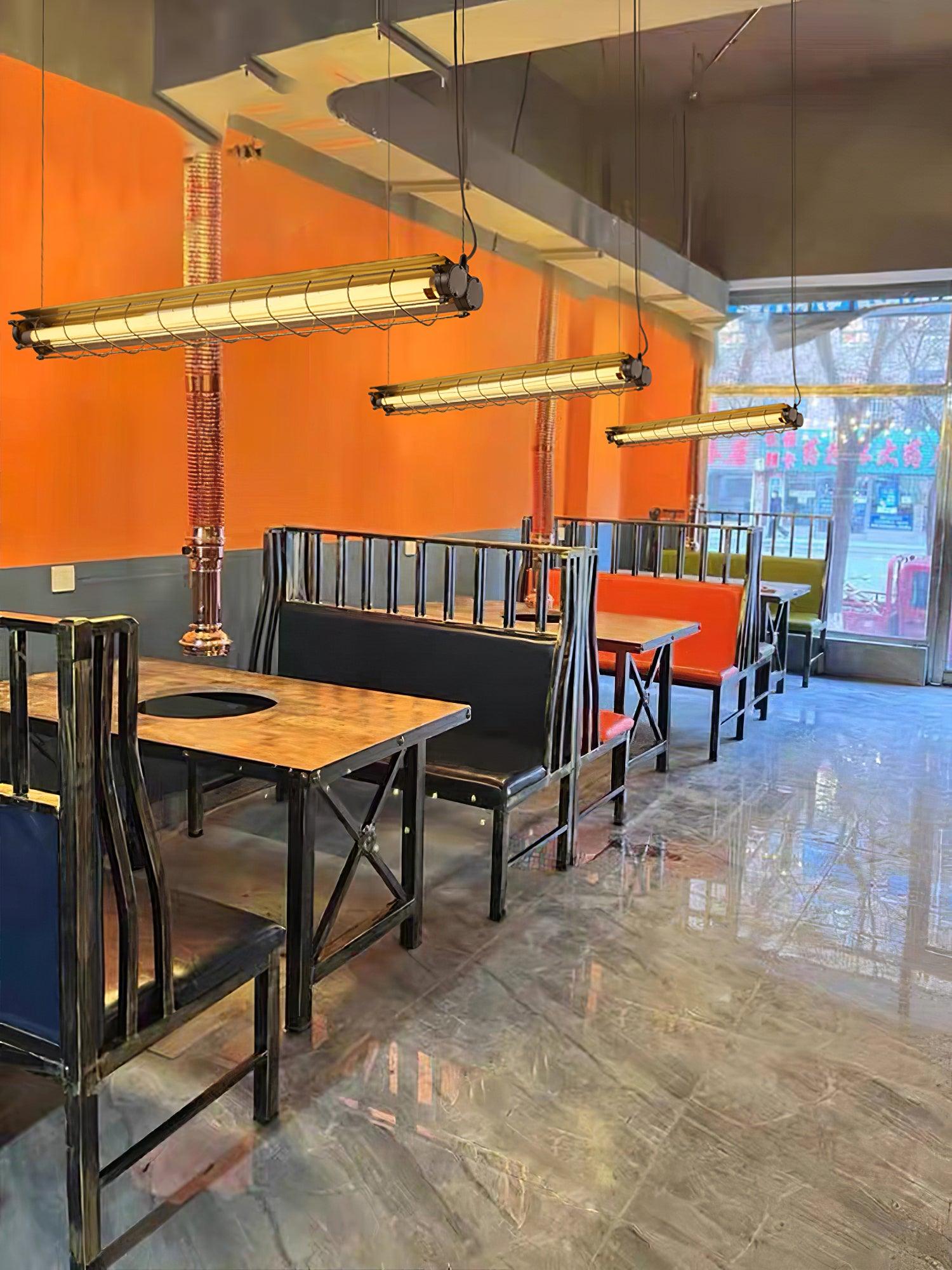 Several Artisan Glass chandeliers in a cafe with an orange wall and wooden tables