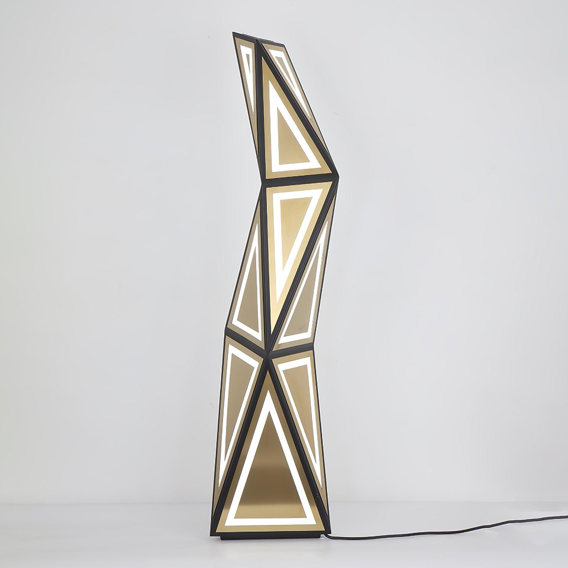 Lit geometric floor lamp on a pale background, with black cord running right from the base