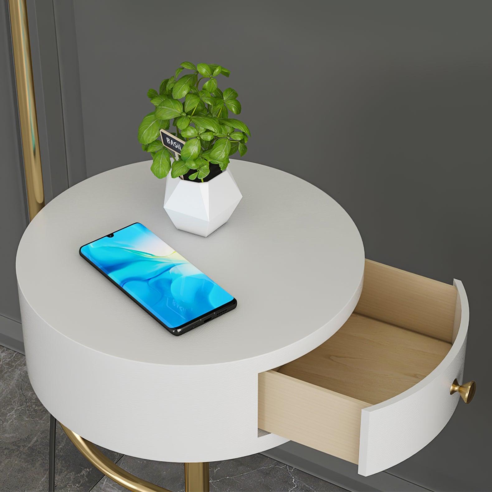 Close white circular table with phone and potted plant, open pale wood drawer, curved white front and gold knob