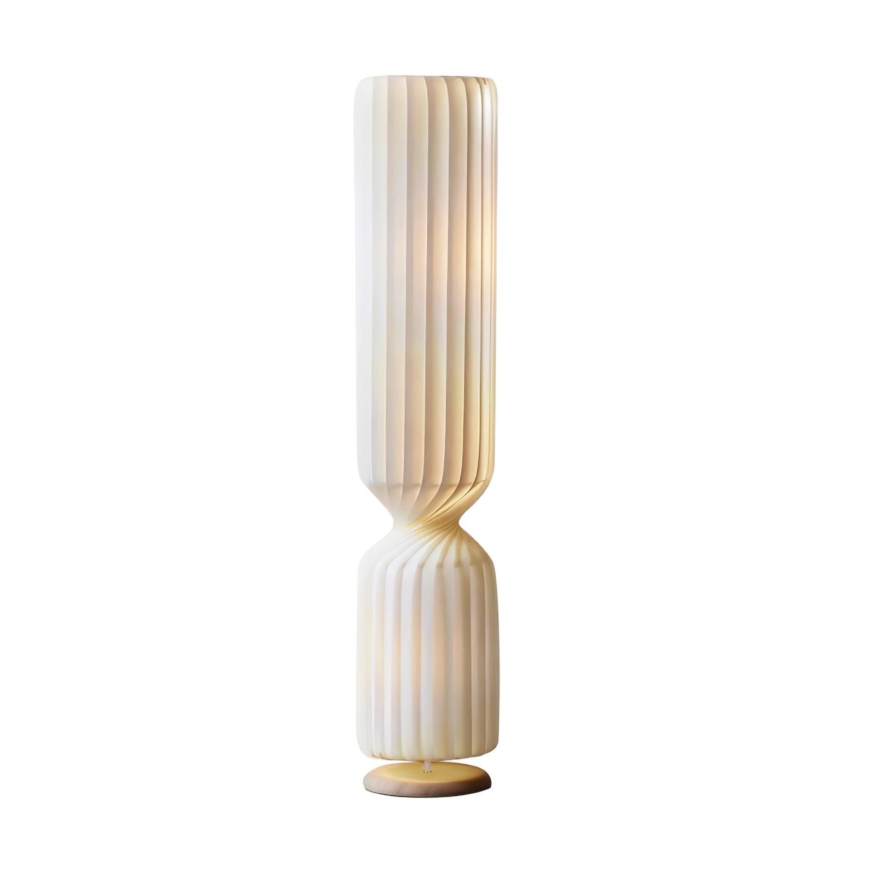 Large isolated lit white pleated Twist lamp with long upper section and twisted waist above short lower section and pale base