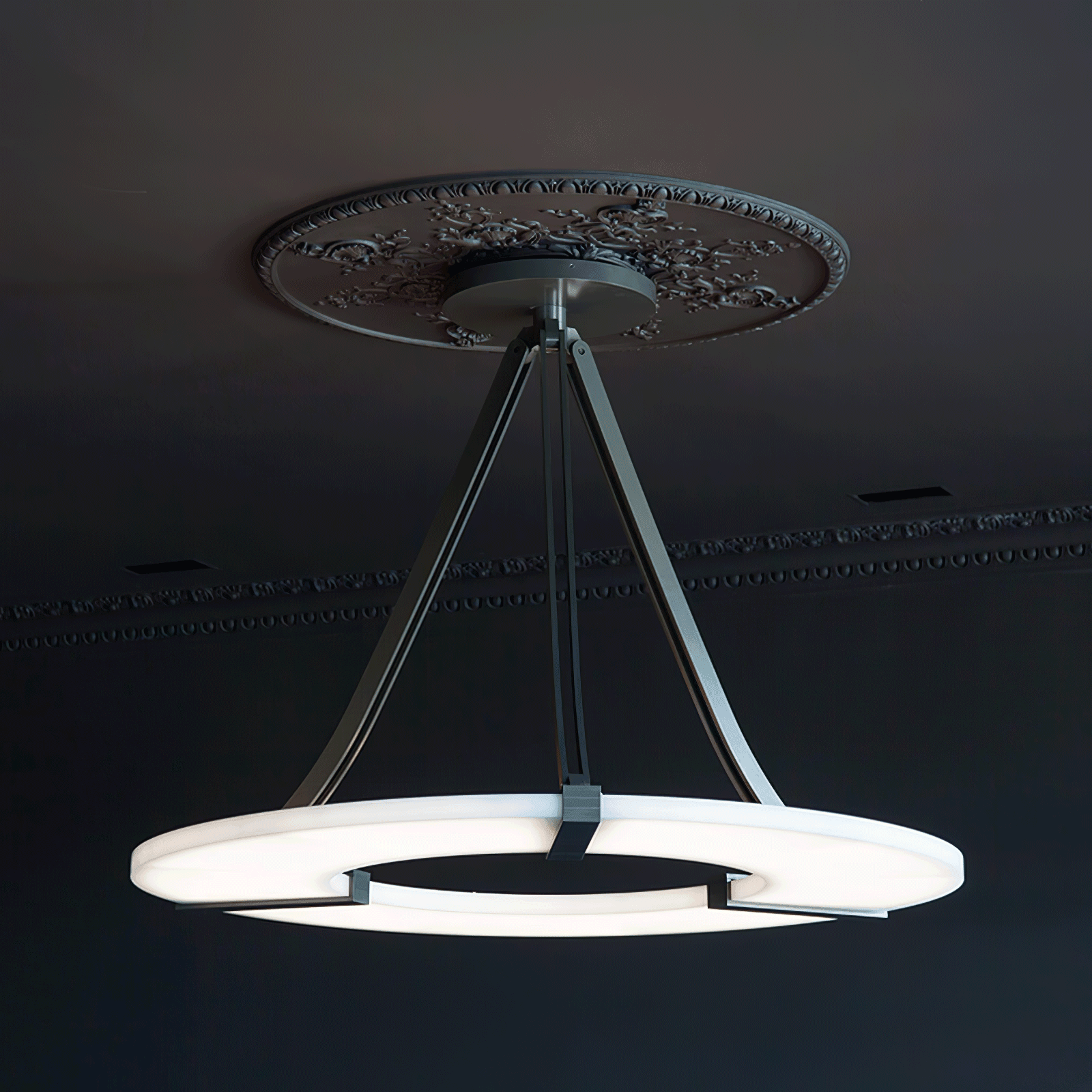 Side view of lit halo pendant beneath floral ceiling medallion and cornice in a dark room
