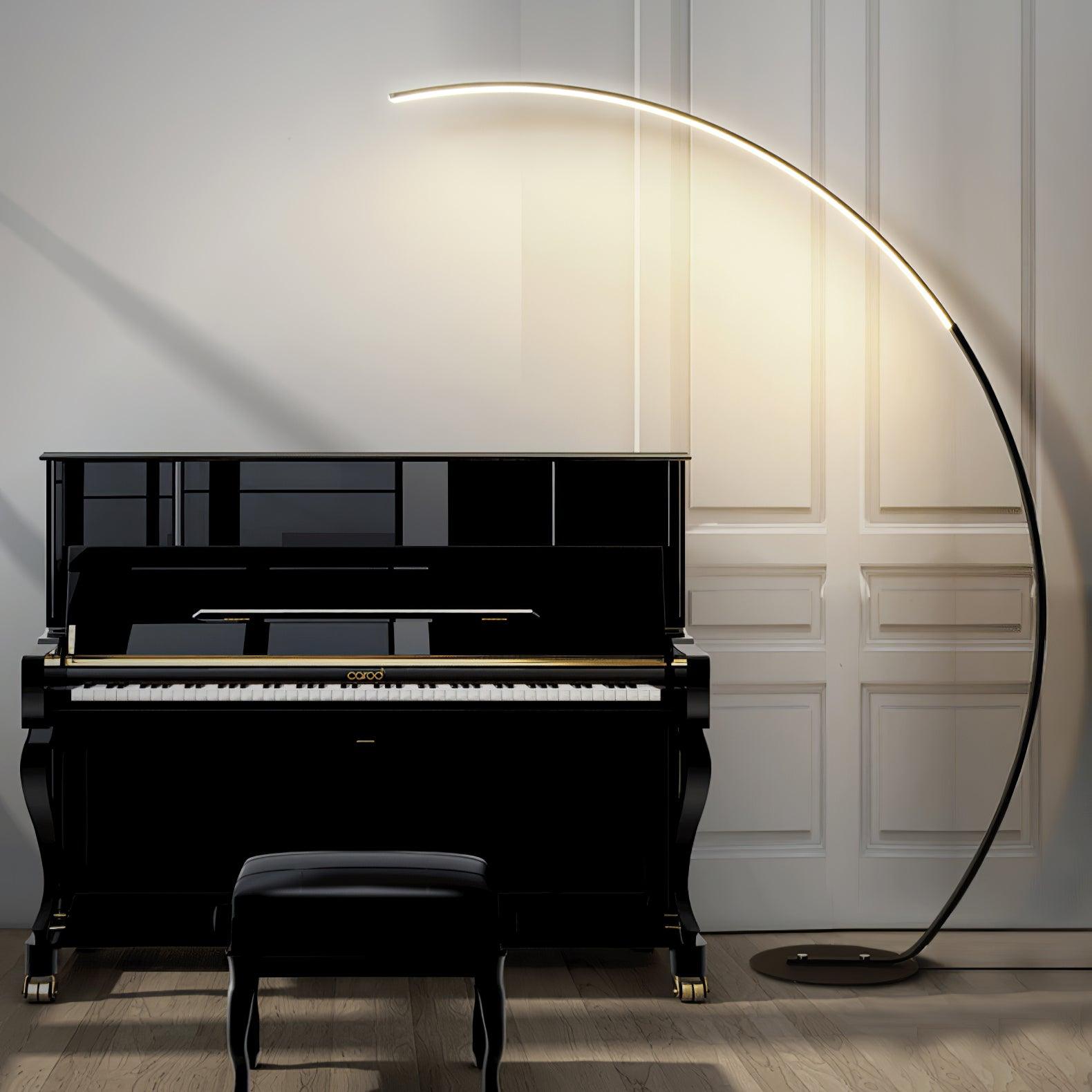 Black Arc floor lamp beside upright piano and bench, with upper illuminated curve against pale moulded wall