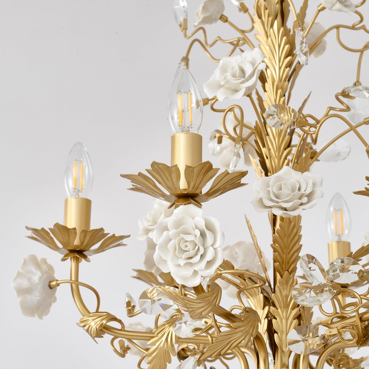 Unlit candle-bulb detail with gold leaf-shaped cup, layered white ceramic roses, curled metal branches and clear faceted buds