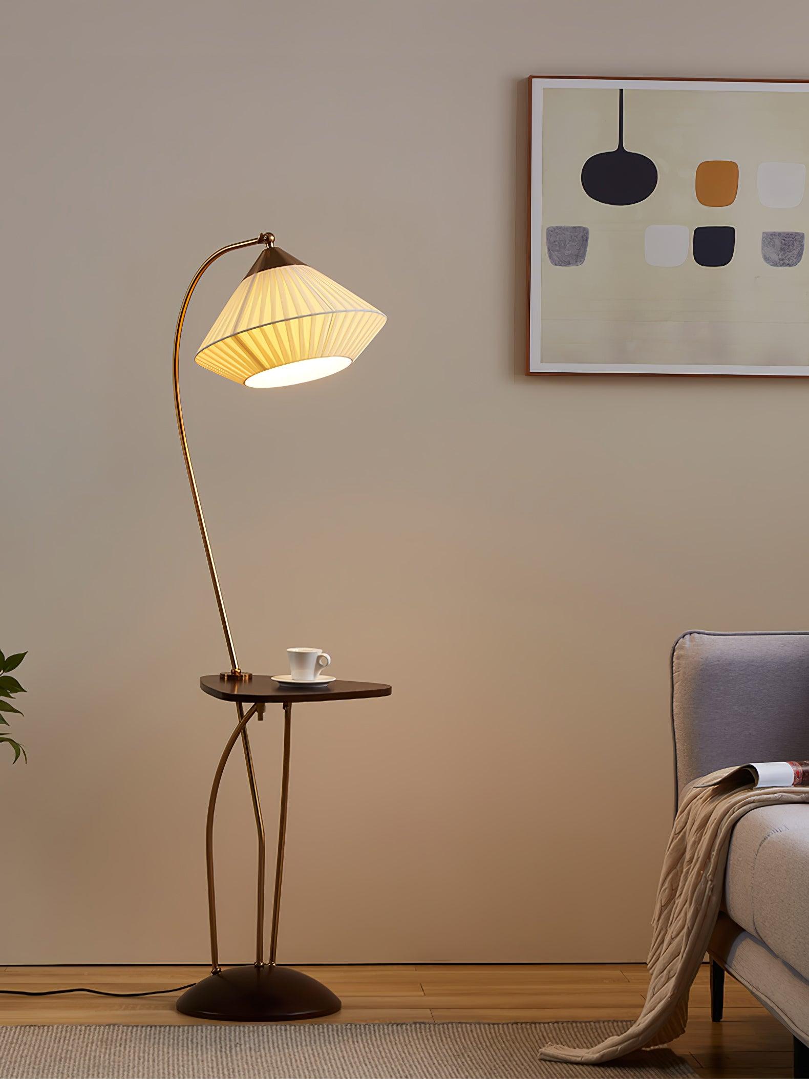 Tall view of lit Curve beside a grey armchair with a magazine and throw beneath abstract wall art