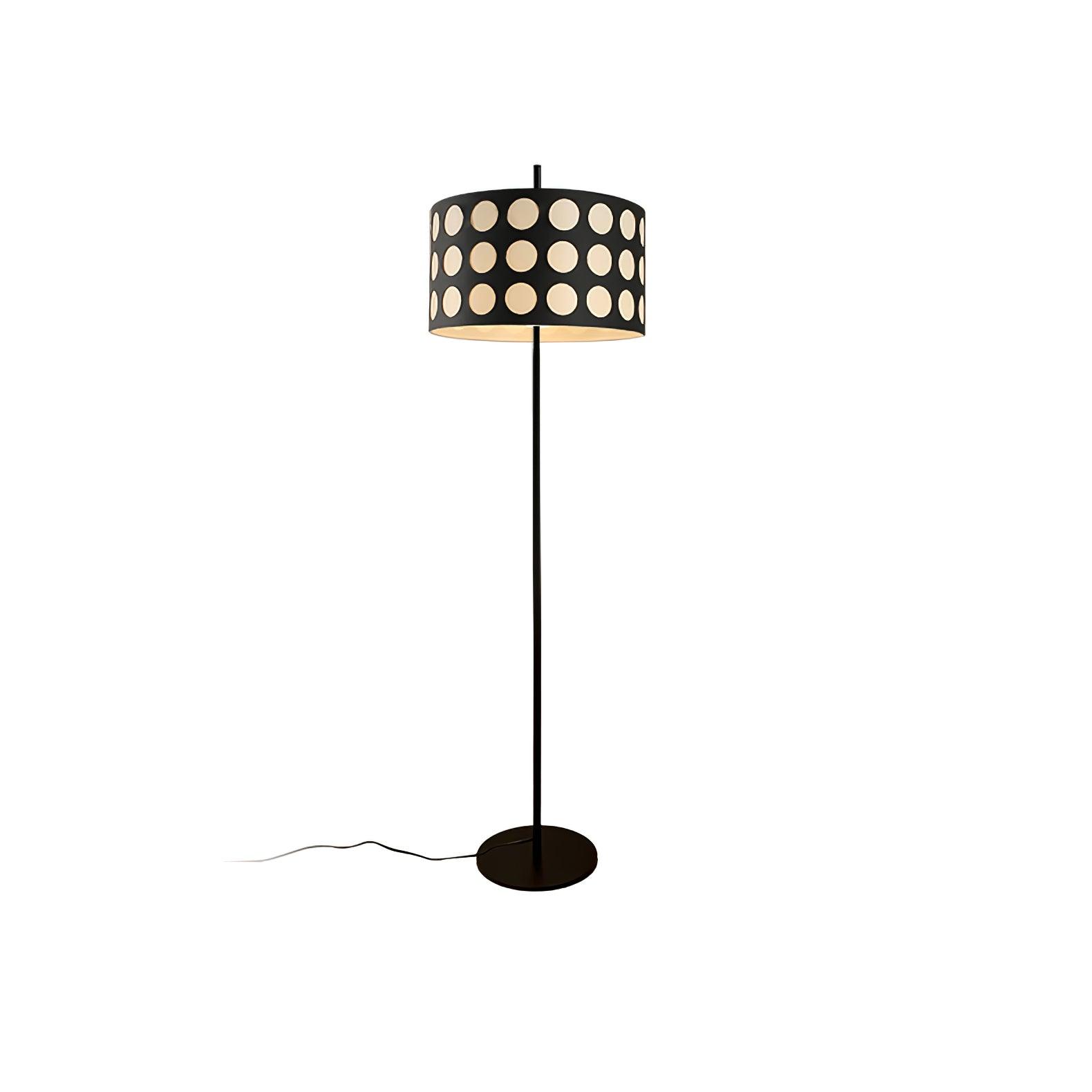 Isolated straight floor lamp with pale dotted black drum shade, circular black base and cord trailing left