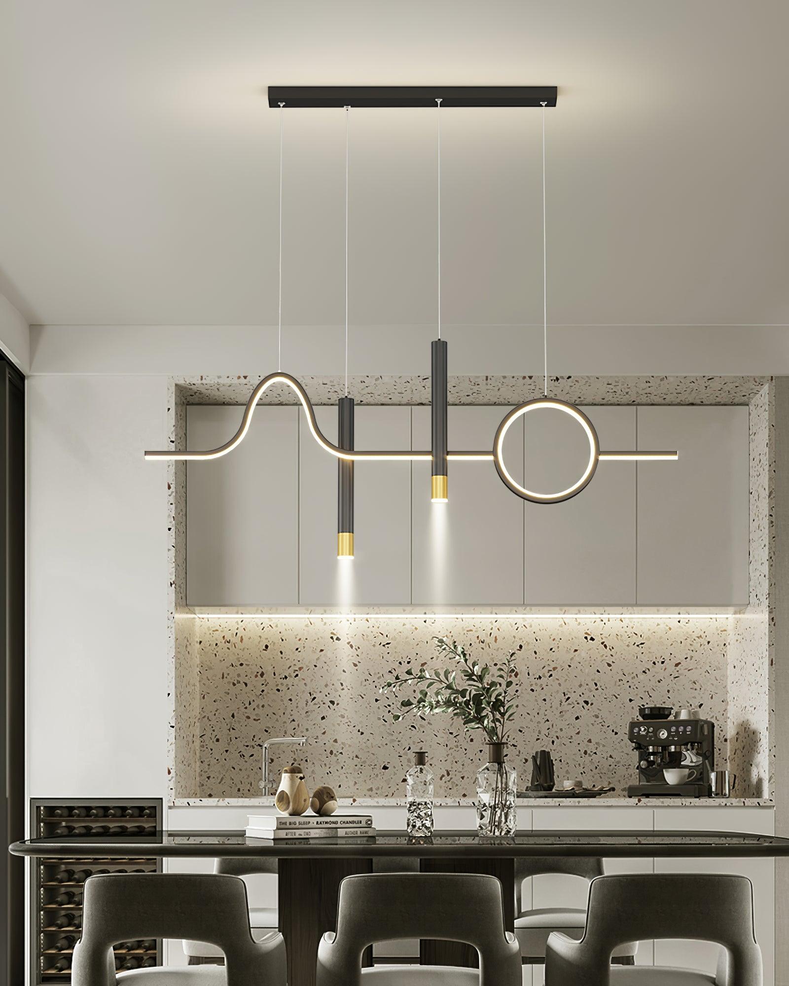Black lit pendant over a kitchen island with three pale stools, branch vase, coffee machine and wine fridge
