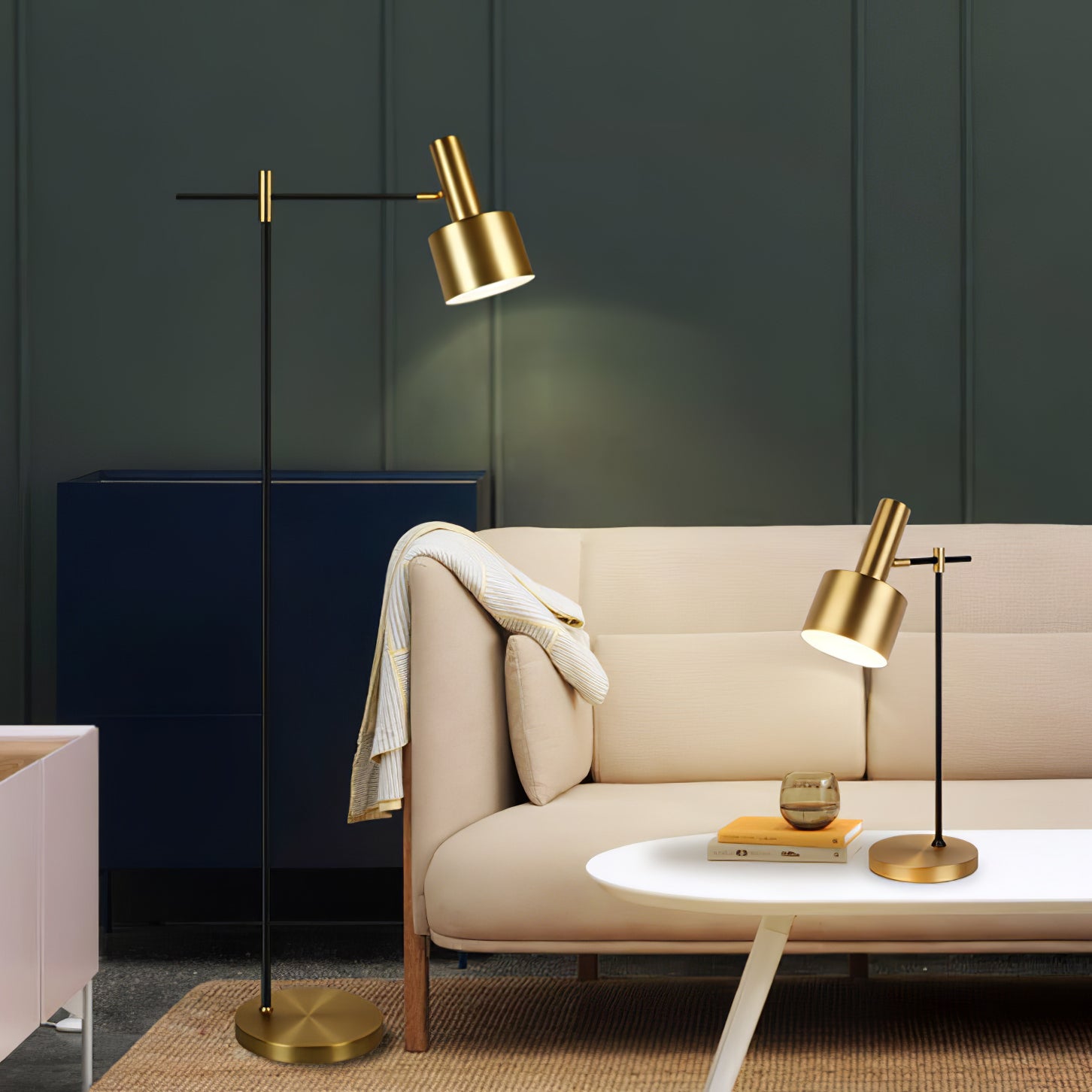 Tall gold-headed floor lamp and separate matching table lamp beside cream sofa, white table and navy cabinet