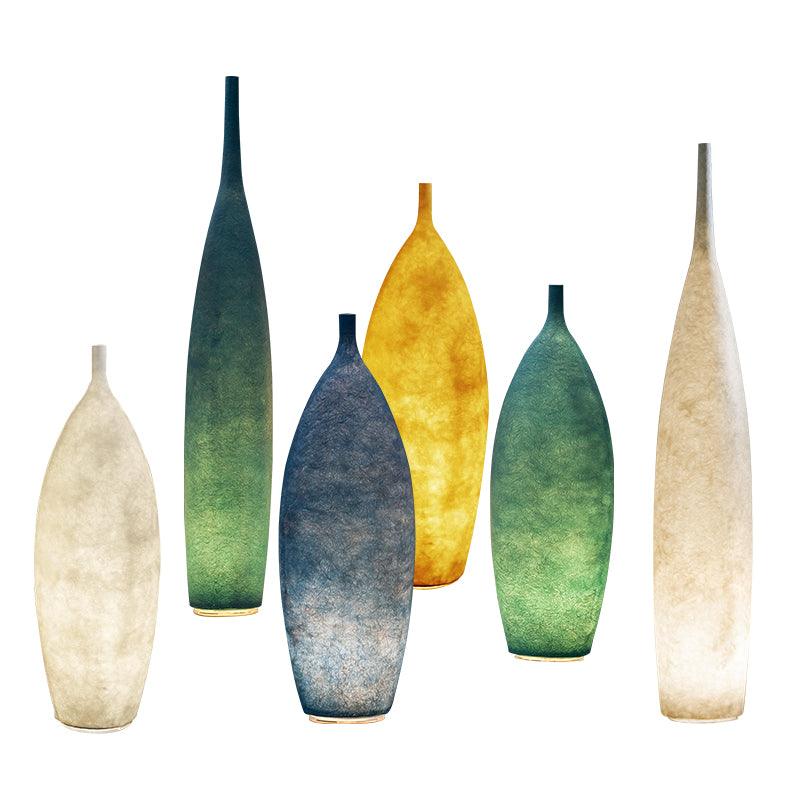 Six glowing bottle-shaped lights at two heights in pale, blue, green and yellow against white