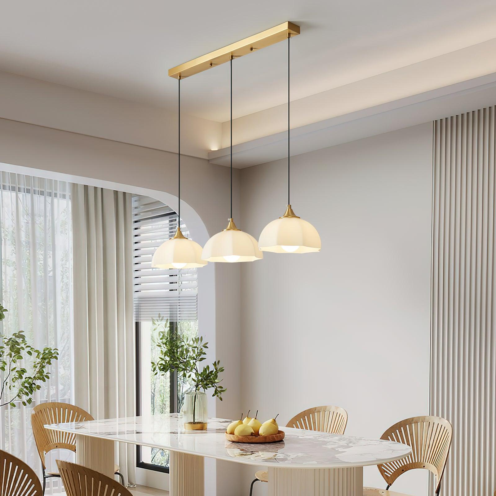 Three white glass pendants on long brass ceiling bar above dining table