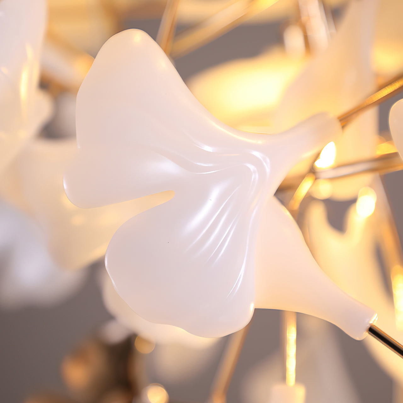 Close-up of glossy white fan-shaped leaf with shallow vein relief and central notch on a gold-tone stem