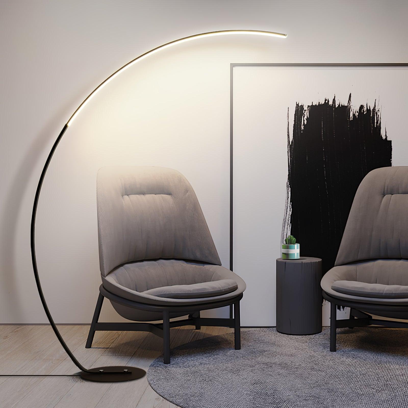 Black Arc floor lamp by grey upholstered chairs and cactus pedestal table, with abstract black-and-white artwork and round rug