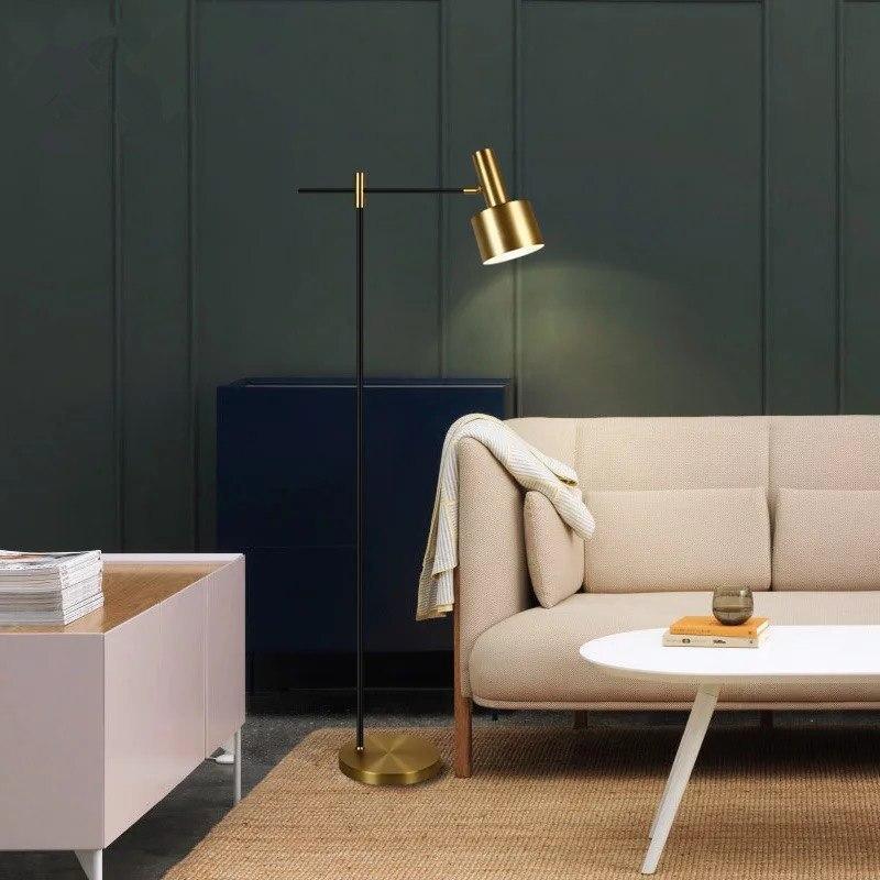 Lit gold-headed floor lamp beside cream sofa and white table, with green panelled wall and blue cabinet