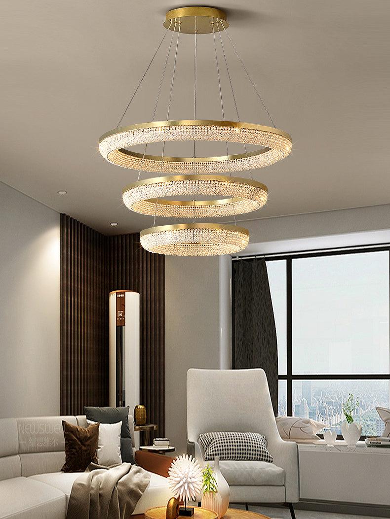 Three-tier crystal ring chandelier above a living-room coffee table and pale armchair