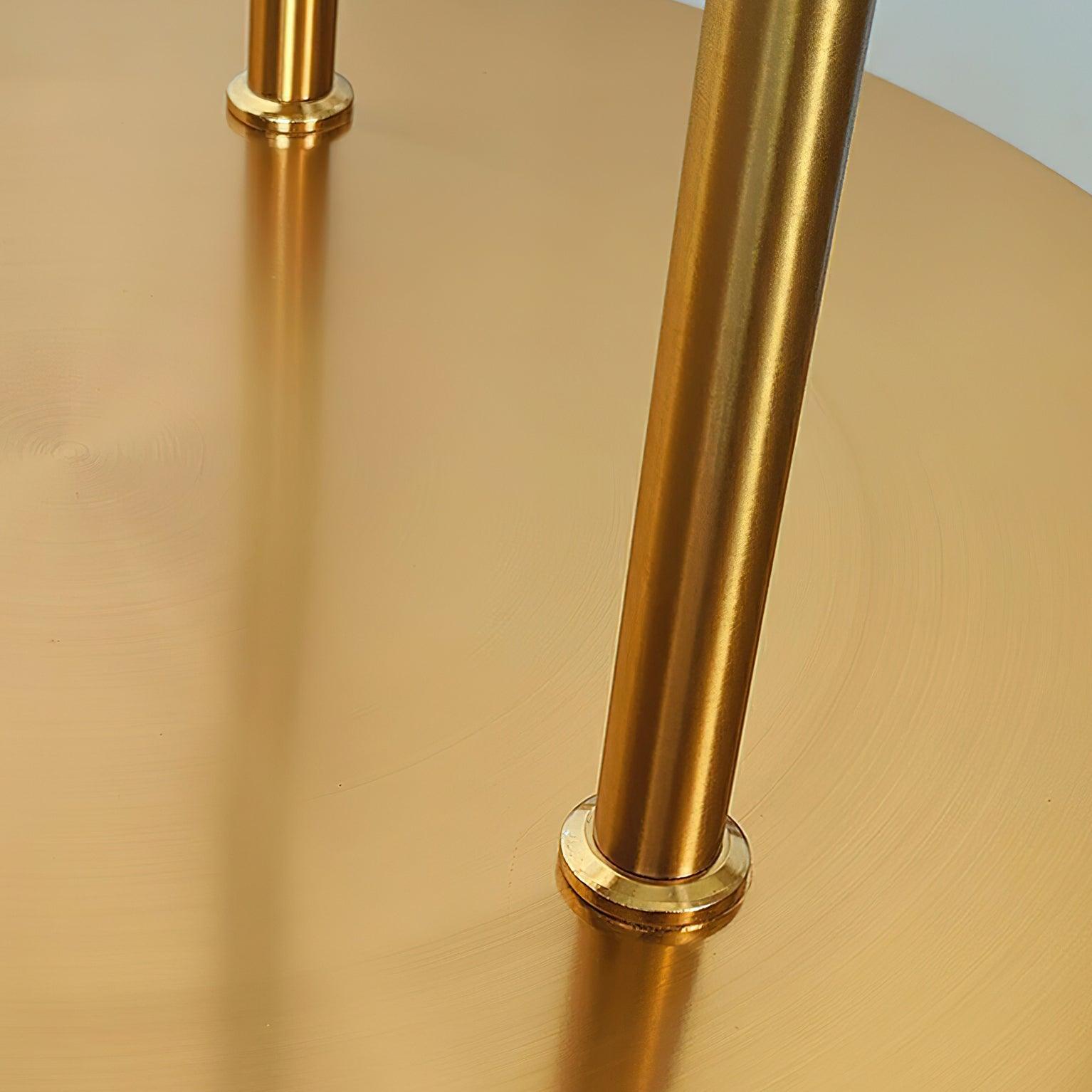 Macro view of gold-finish stems and attachment collars on the circular metallic floor-lamp base