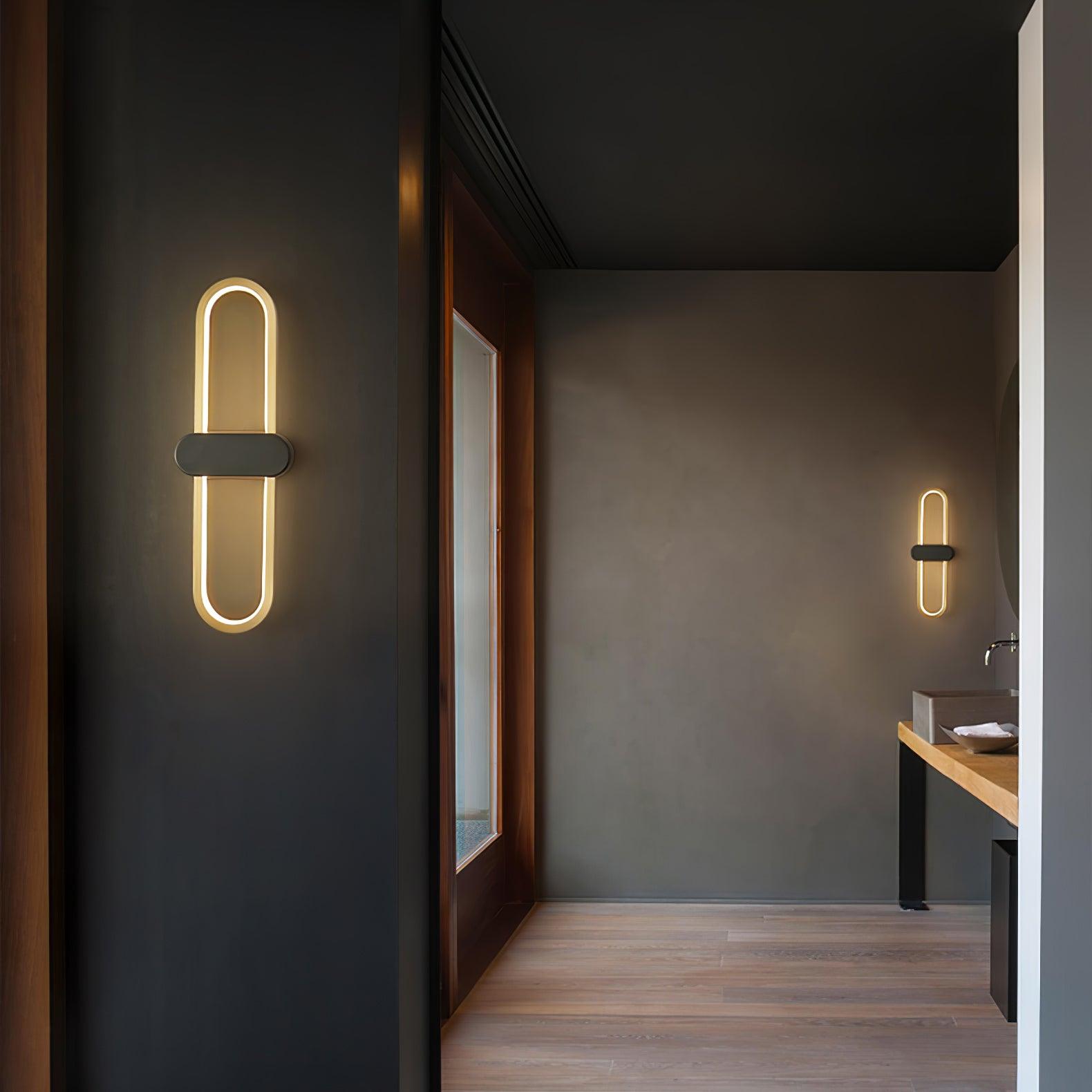 Two gold-loop wall lights with black centre covers along an interior passage with a basin at the far end