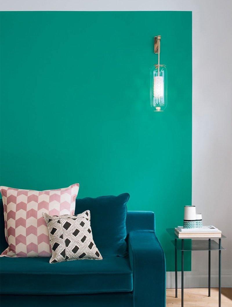 Glass wall lamp against a teal living-room wall