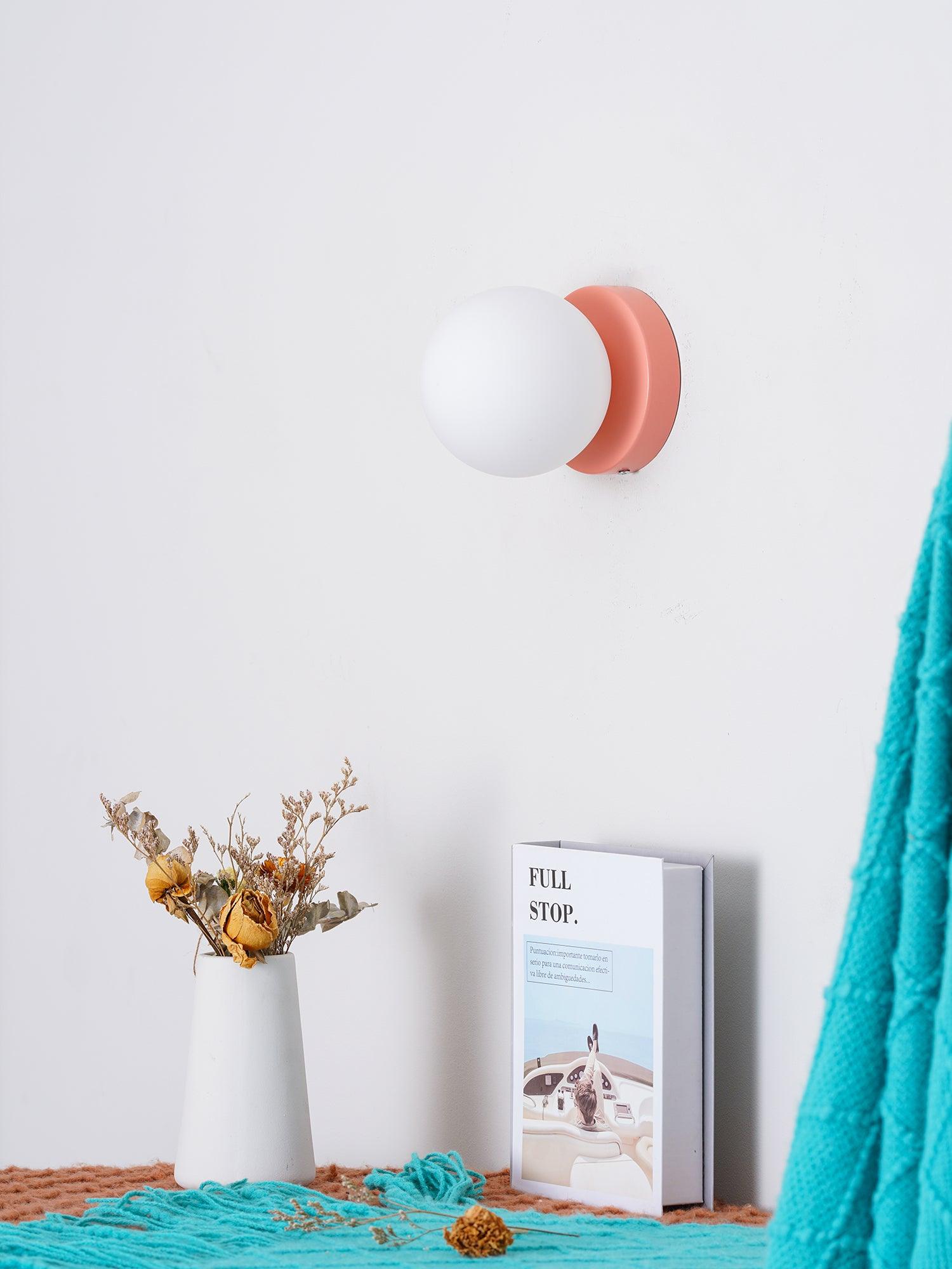 Unlit pink-plate globe above flowers and a propped book