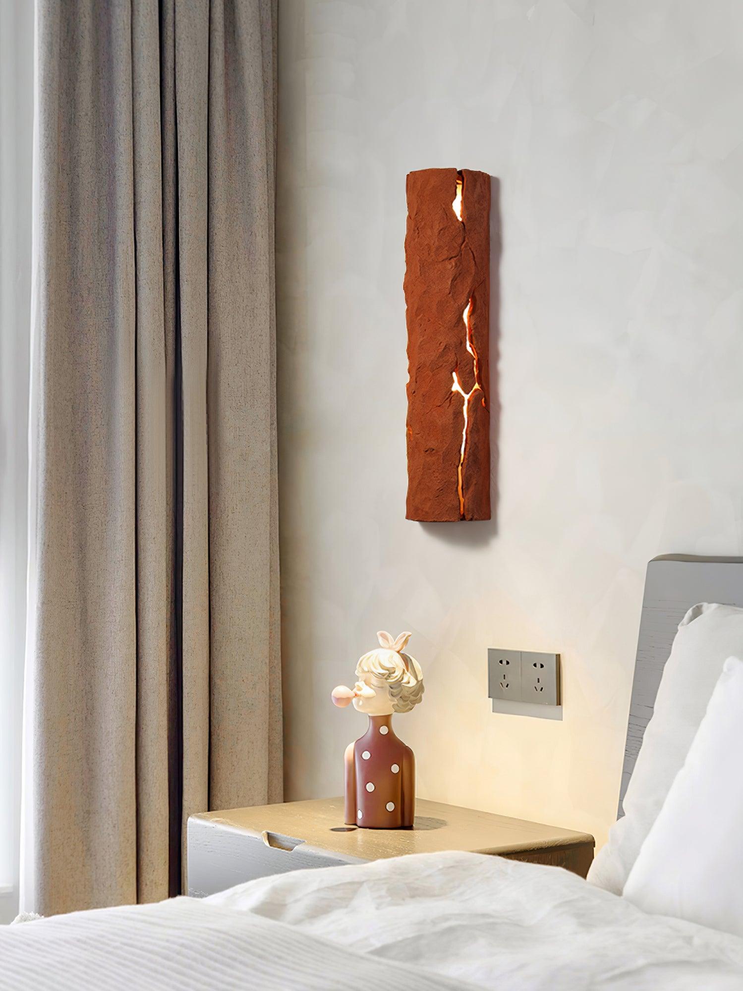 Terracotta-looking fissured wall light beside curtain and bed above a character sculpture; no separate finish selection