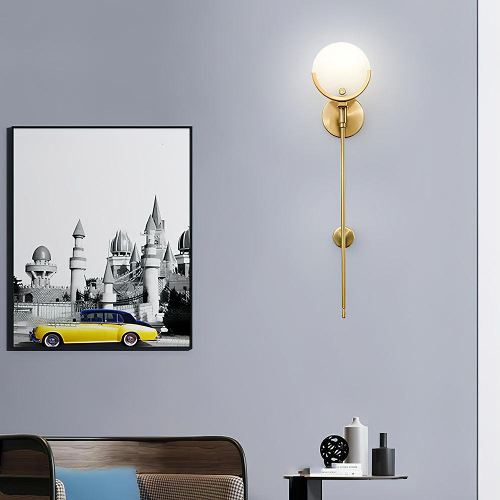 Long-stem Ava light on a grey wall beside a framed castle and yellow car print, above a wooden bedhead