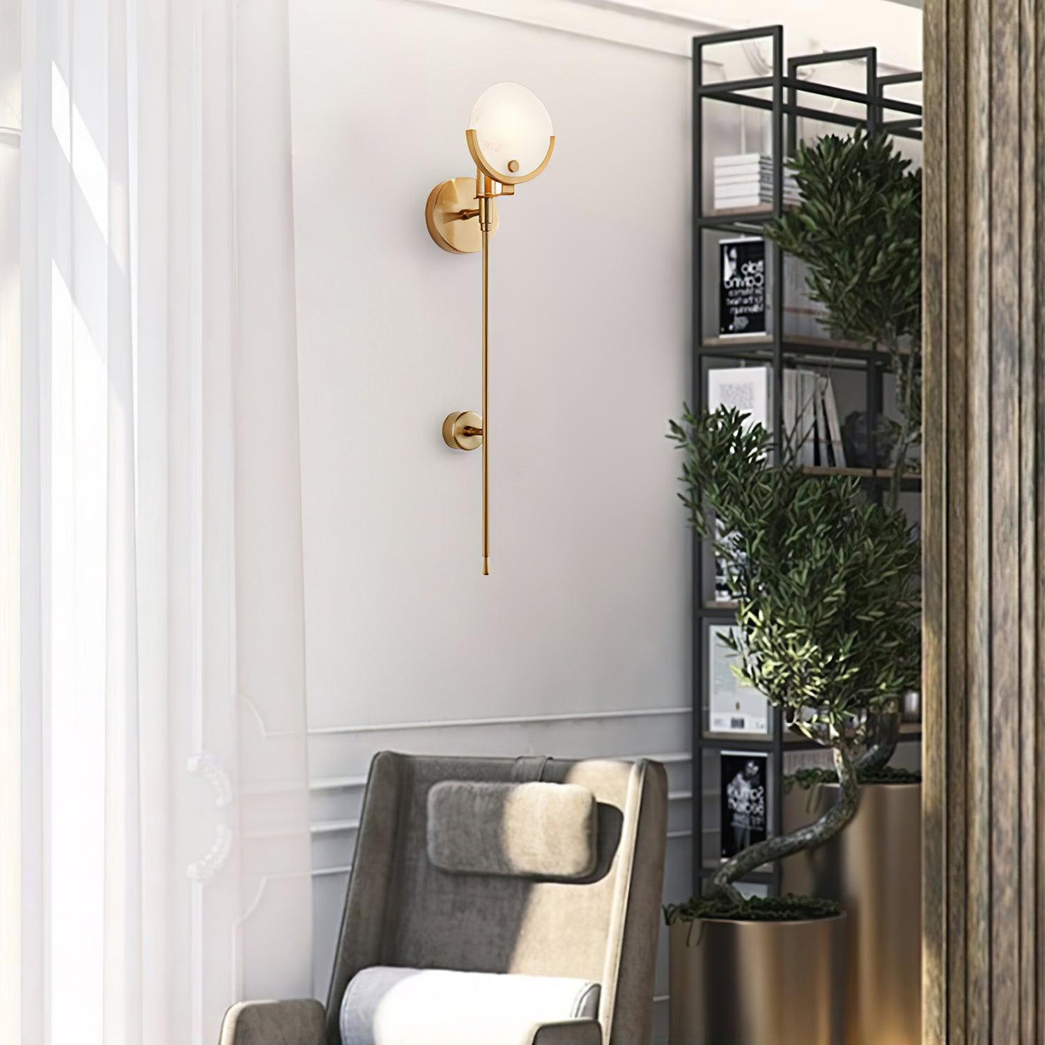 Long-stem Ava wall light above a pale chair beside a window, shelving and an indoor plant