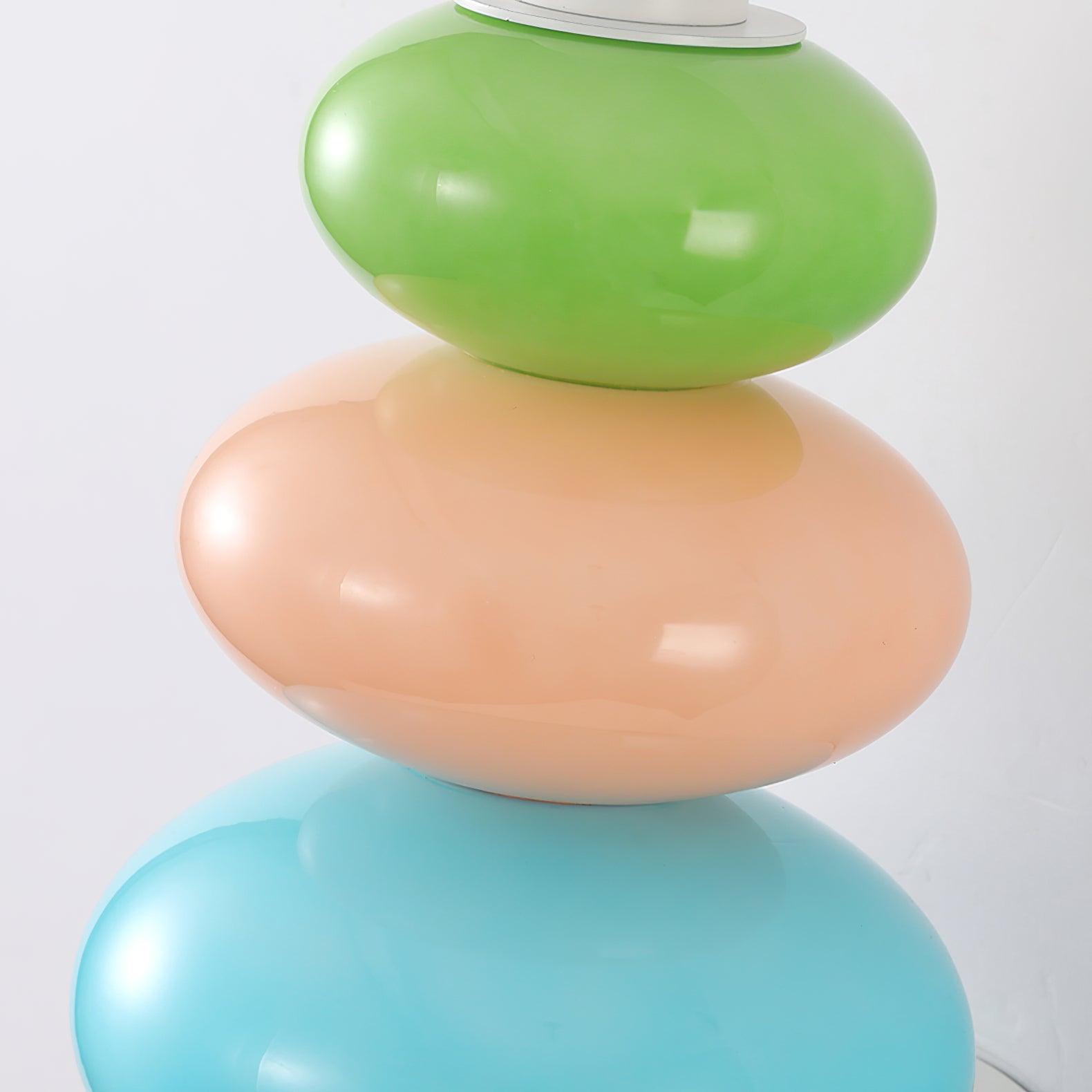 Close unlit glossy green, peach-pink and blue rounded glass segments and white upper collar