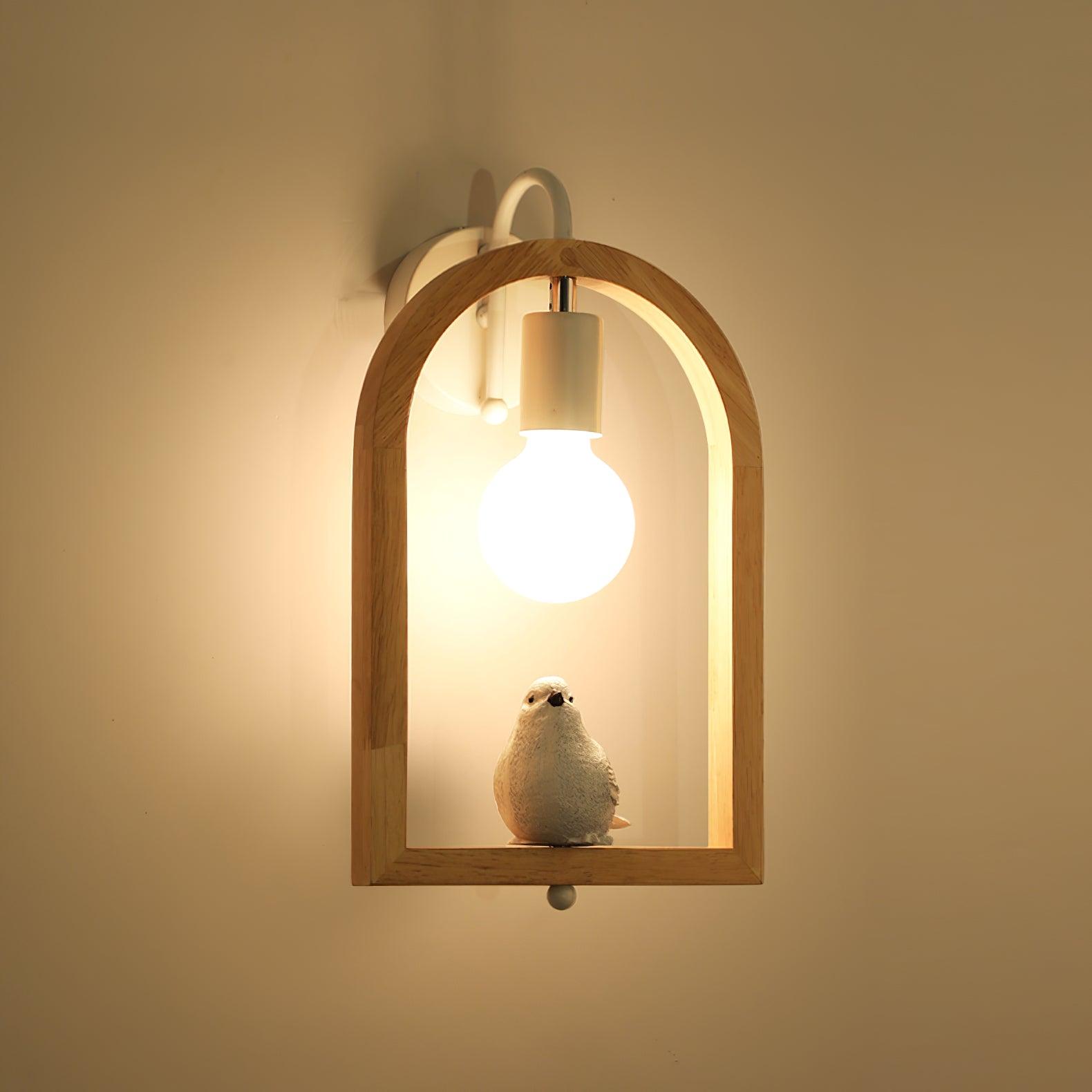 Close view of the bird figurine beneath a glowing bulb, surrounded by the wooden arch and warm light on the wall