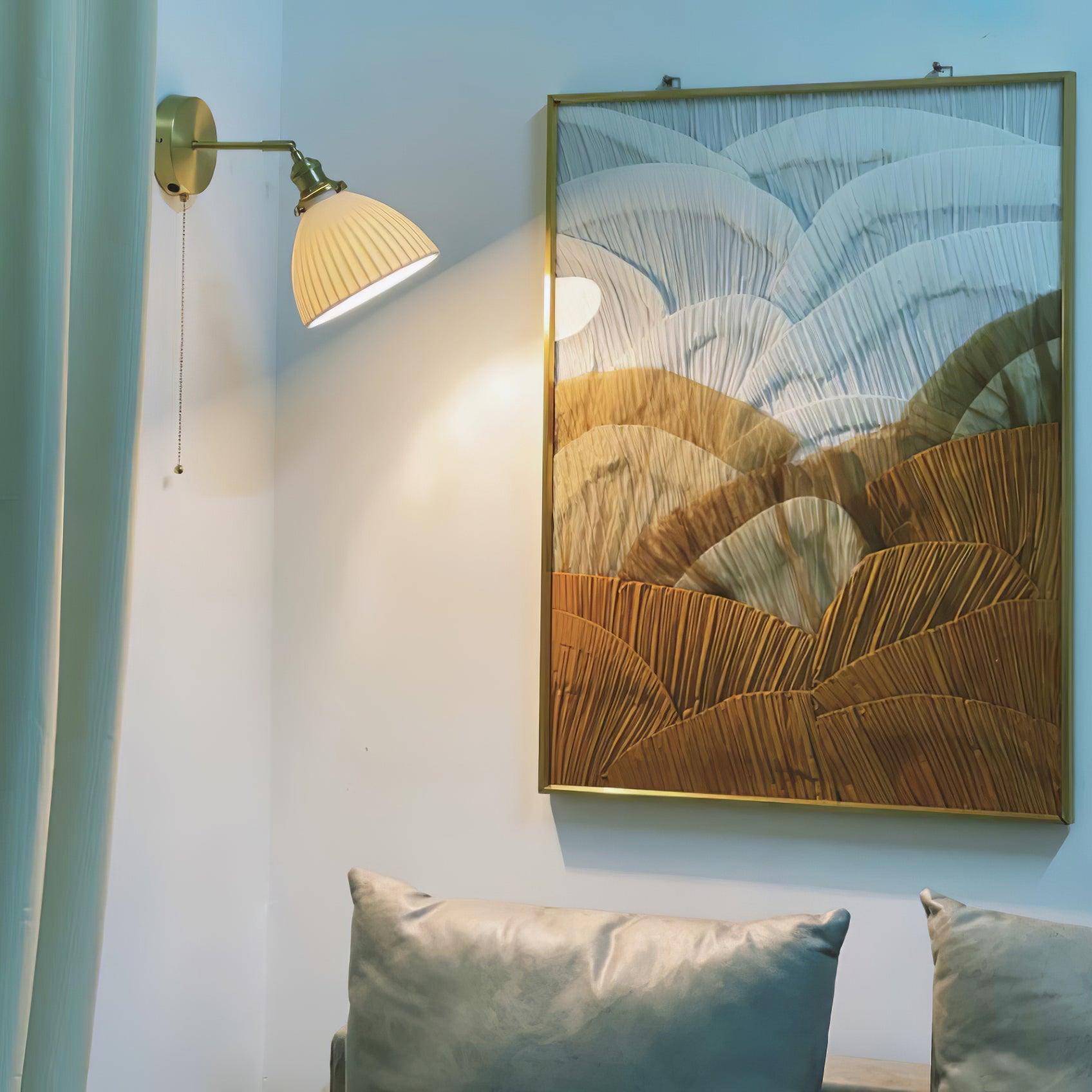Wide artwork-and-sofa scene with a lit ceramic wall lamp and hanging chain at the upper left