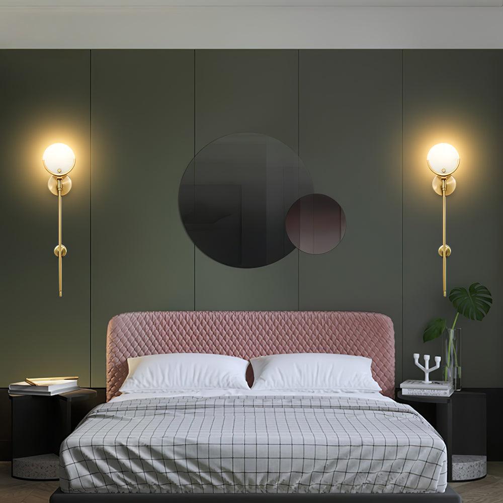 Wider view of two long-stem Ava lights flanking a pink headboard against a green wall