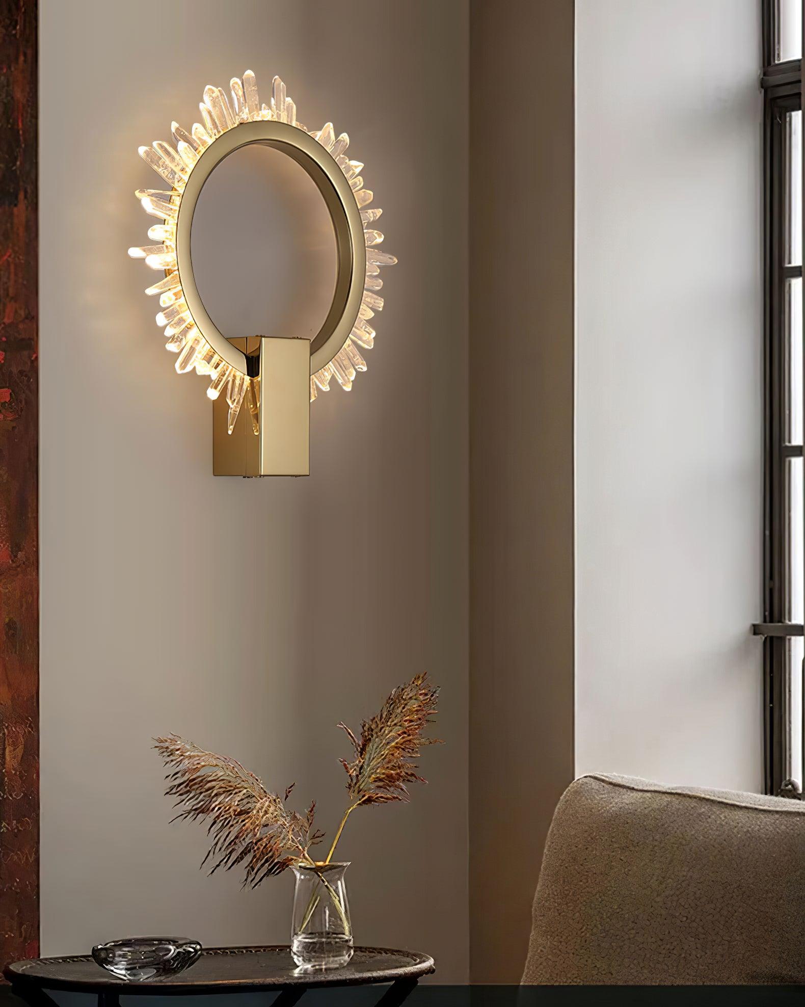 Angled gold crystal wall light above a round side table and dry grasses beside a beige chair