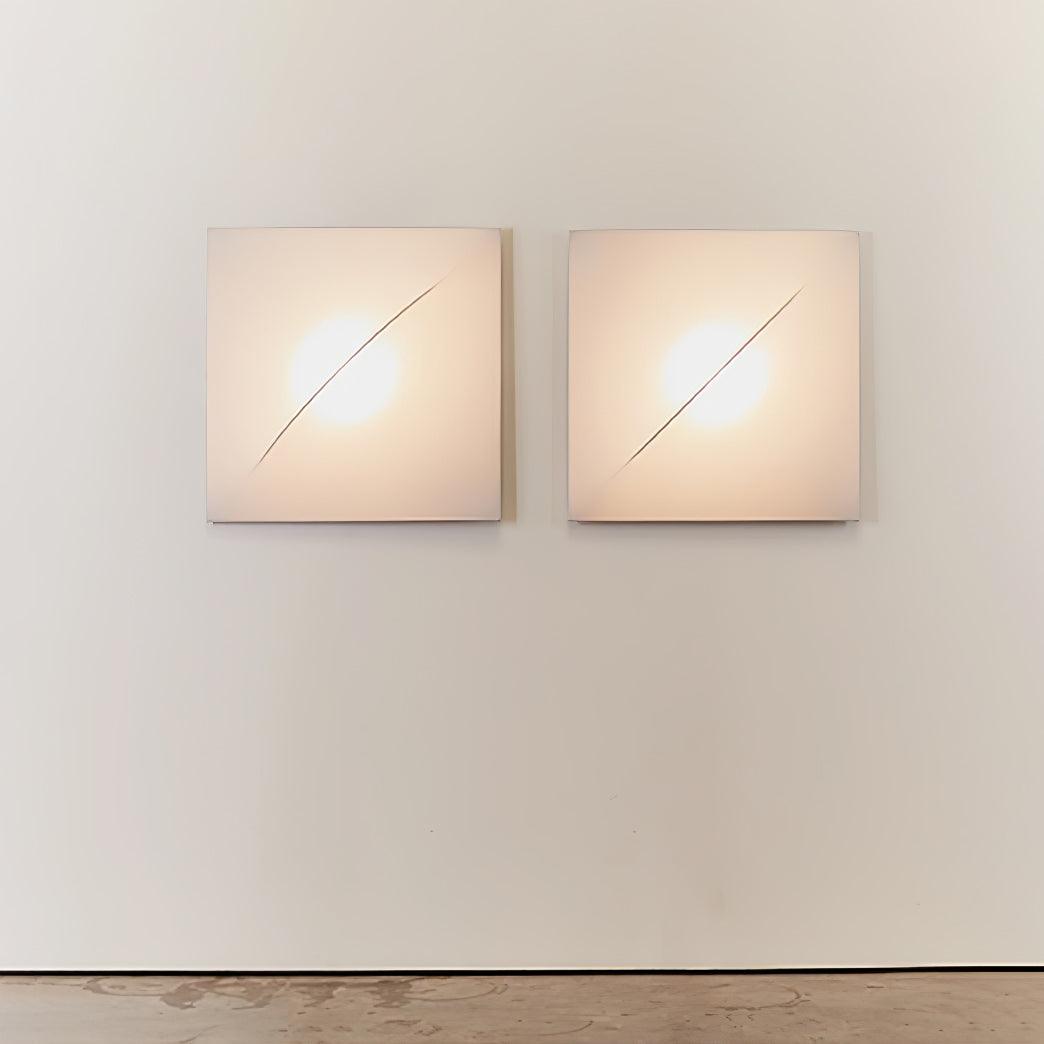Two separate lit square Geometric Series wall panels side by side on a pale wall
