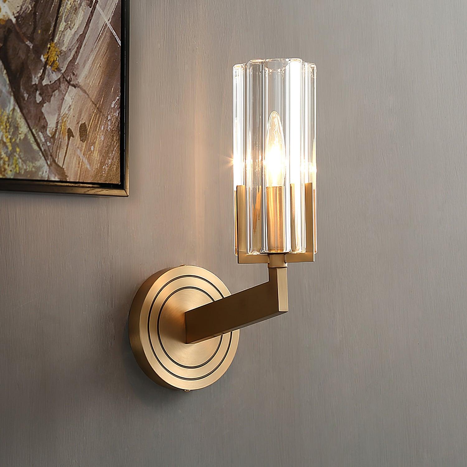 Close lit single clear fluted shade with brass arm and concentric-ring wall plate beside framed painting on grey wall