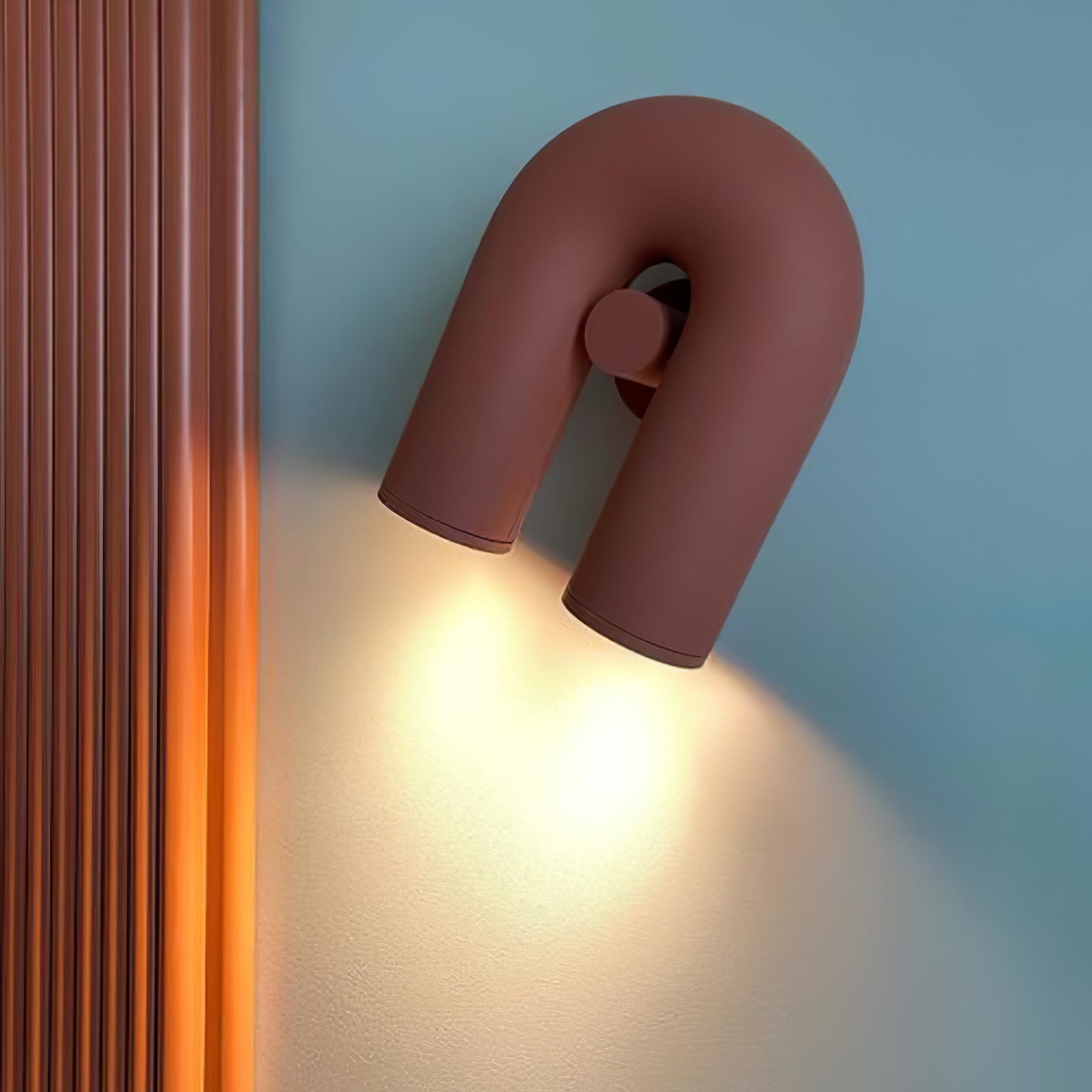 Terracotta Cirkus U-shaped wall lamp tilted beside vertical wood slats
