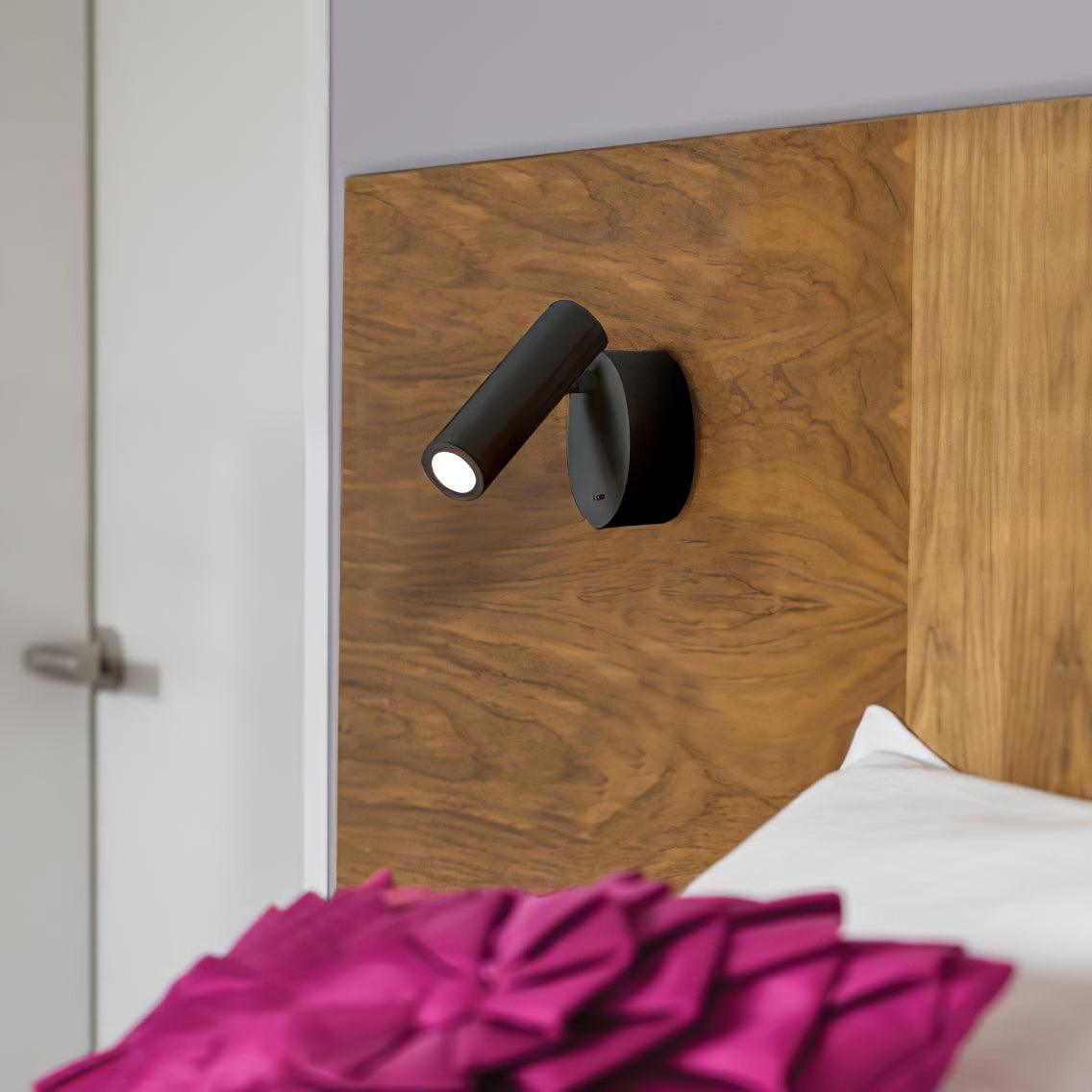 Black reading light on a wood headboard