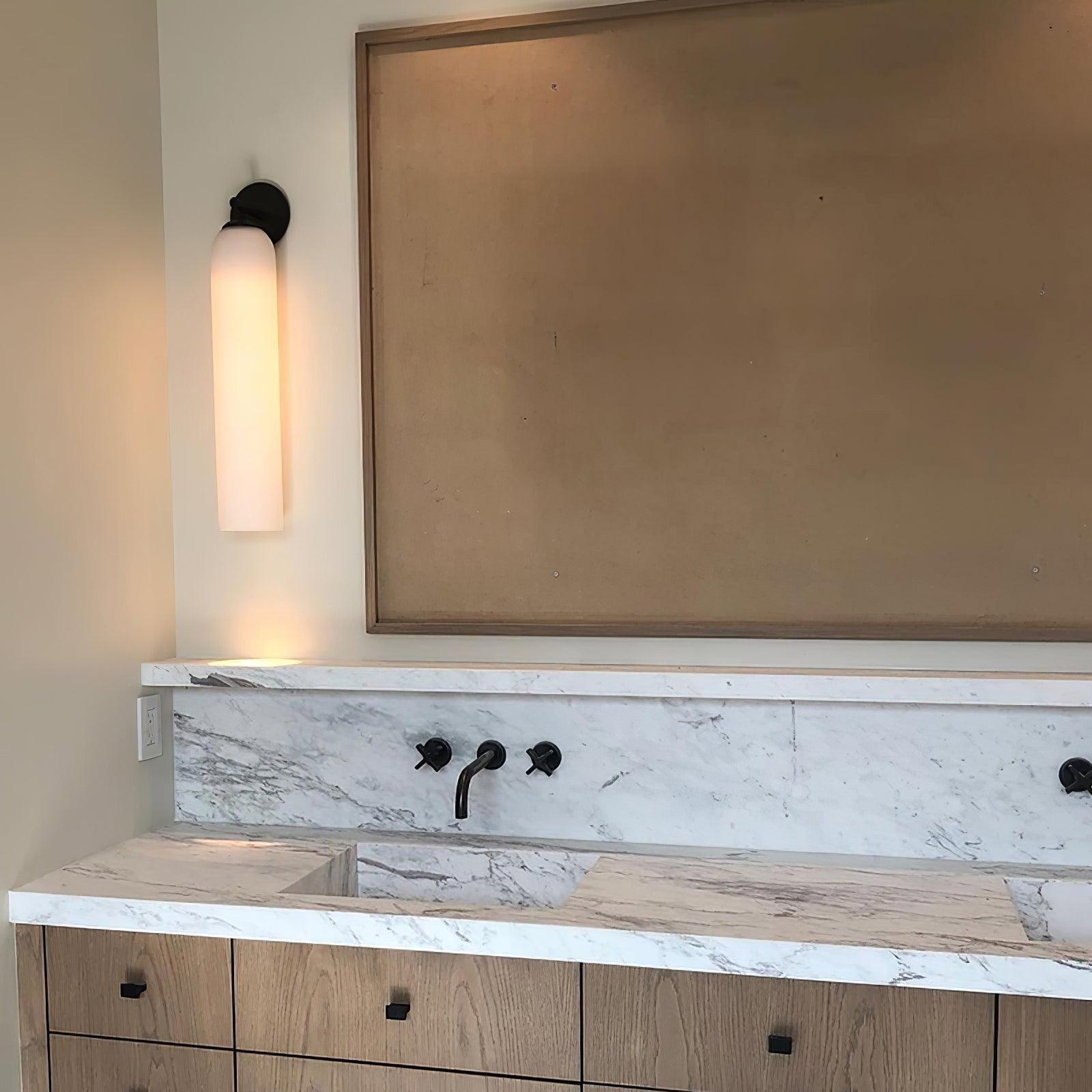 White cylindrical sconce above a bathroom counter