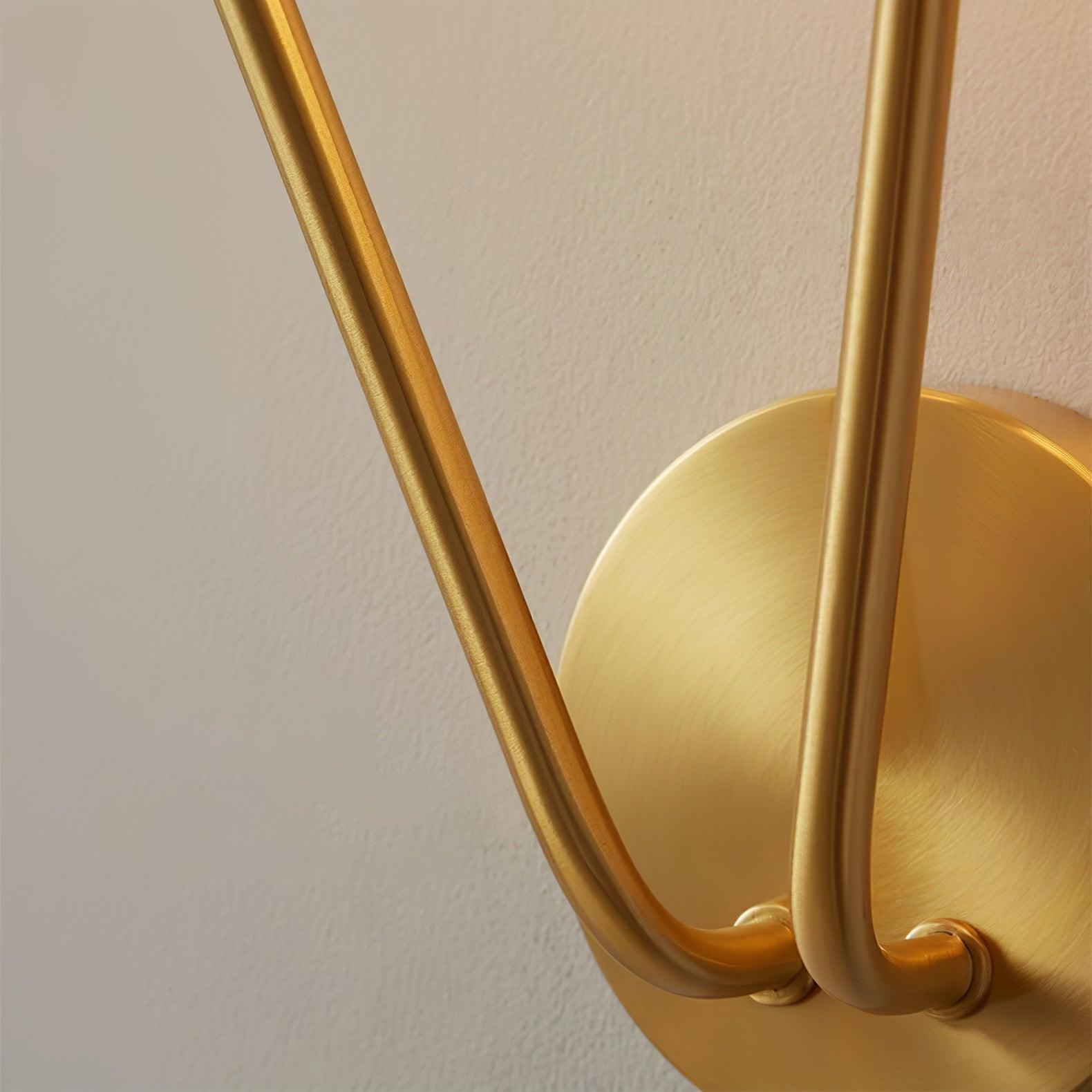 Close round brushed brass-tone wall plate with two curved stem connections on textured wall