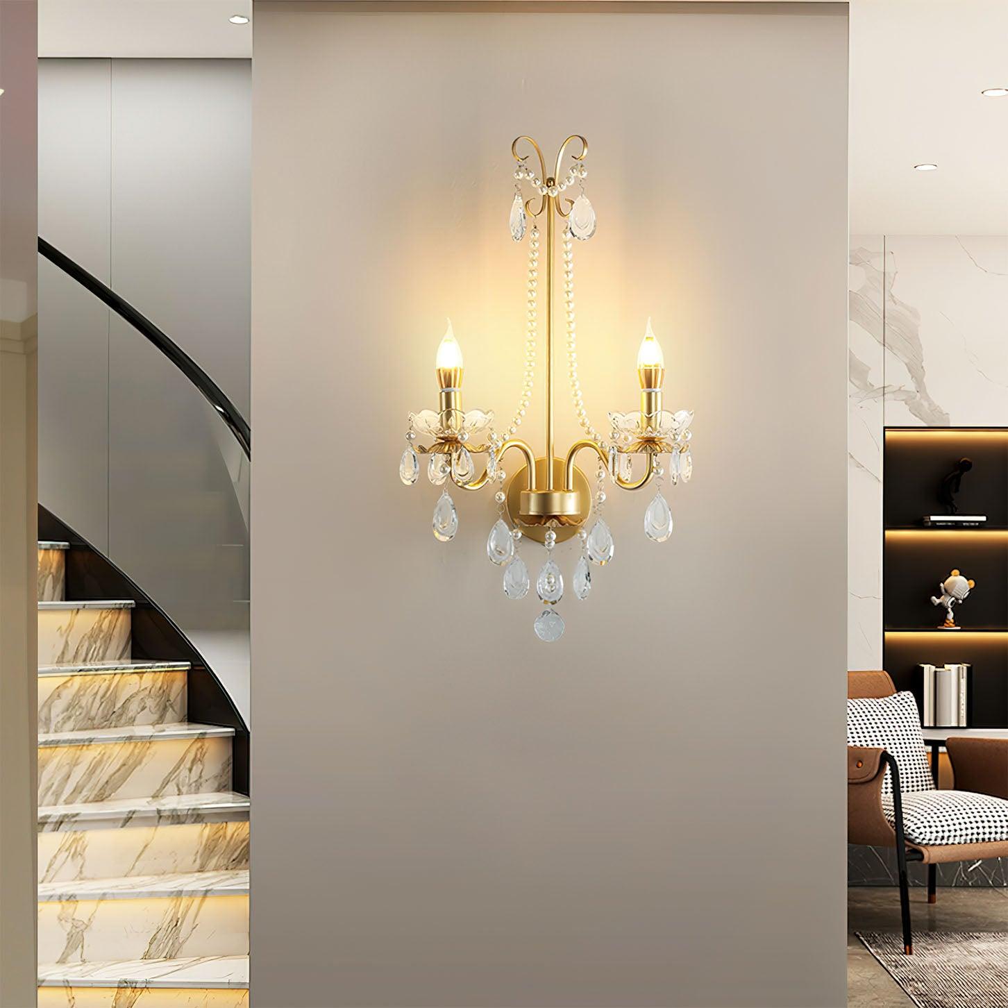 Lit fixture on wall pier between marble-look stairs with black handrail and brown chair beside dark recessed display shelves