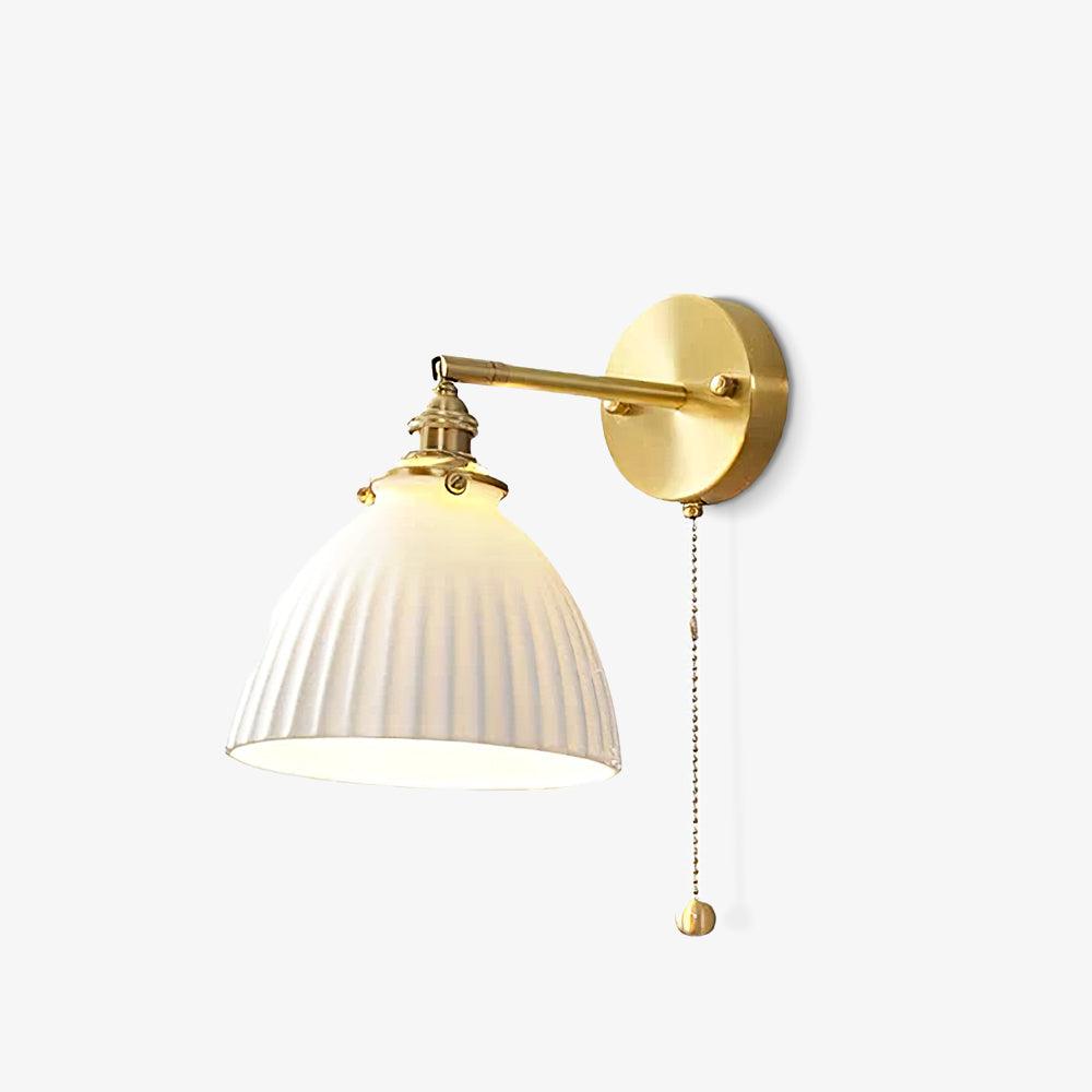 Small isolated white pleated wall light on white, with brass arm, round backplate and hanging chain