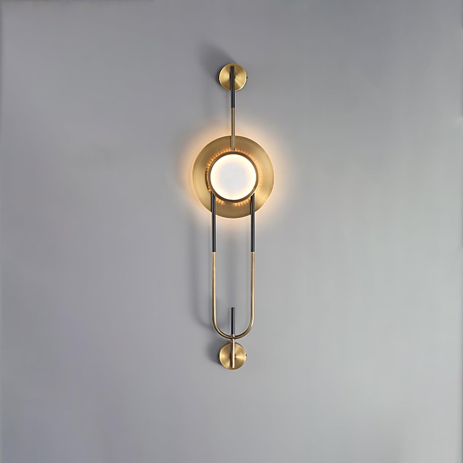 Front view of the illuminated circular marble wall light and gold-and-black loop frame against gray